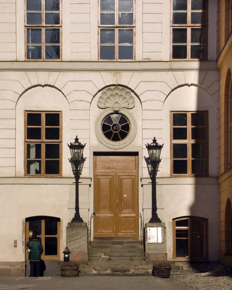 Rehns portal. Brunmålad dörr med ett runt, spröjsat fönster ovanför med siffran 10.