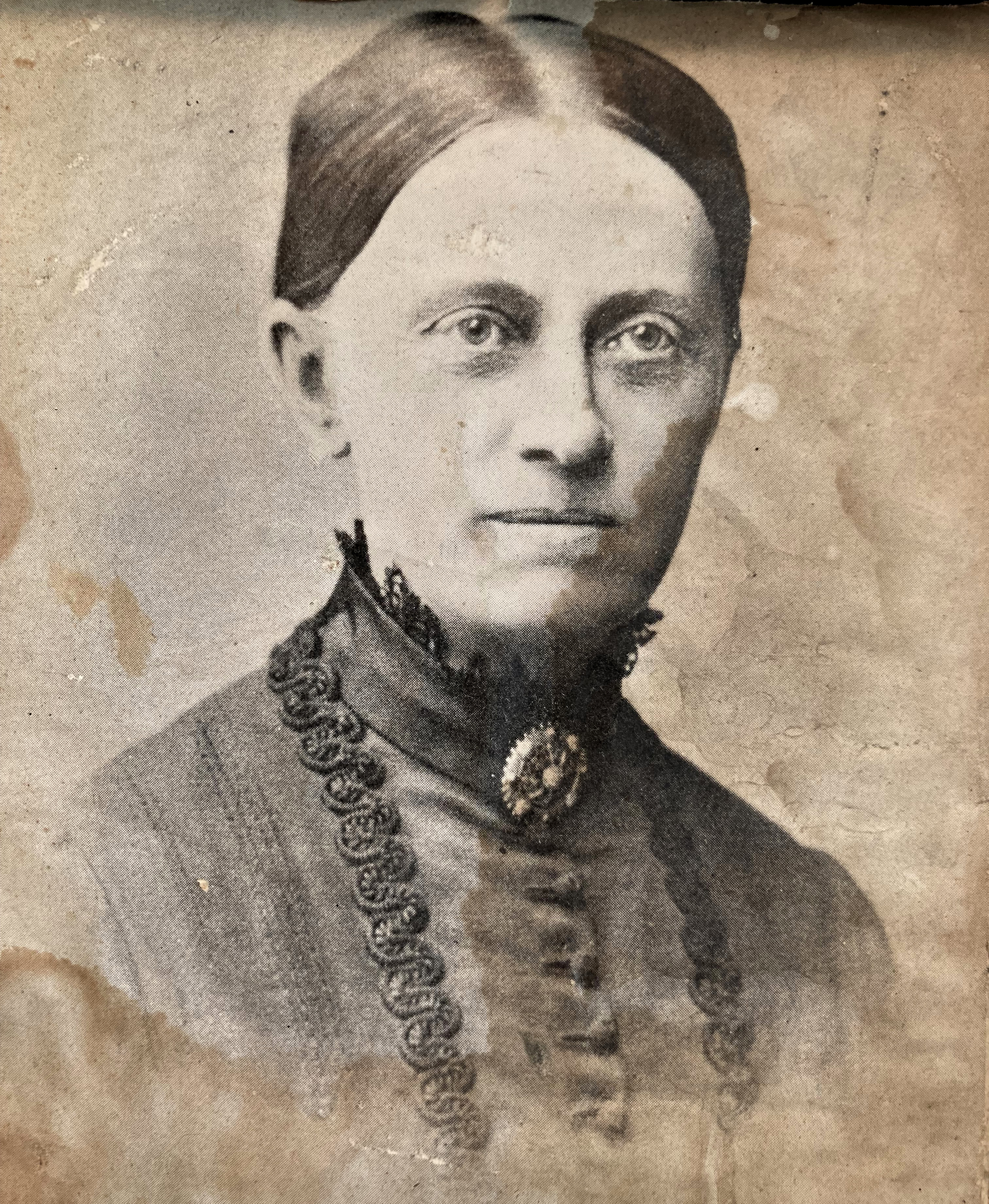 Gammal bild i sepia, porträttbild på kvinna med stram håruppsättning.