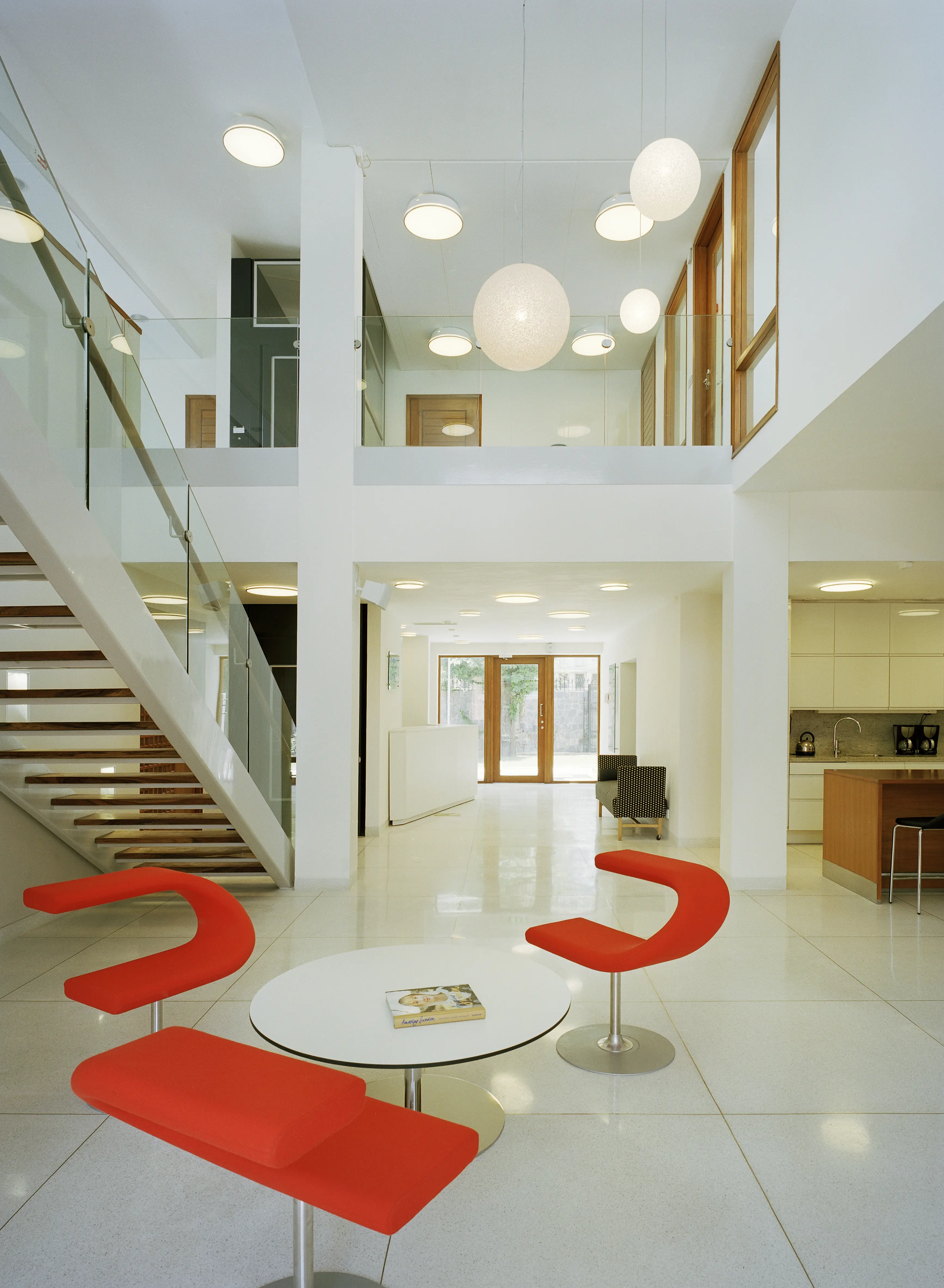 Interiör, ambassaden i New Delhi. Golv, väggar och tak är vita, möbleringen är enkel. Runt en ljusgård går räcken av glas.