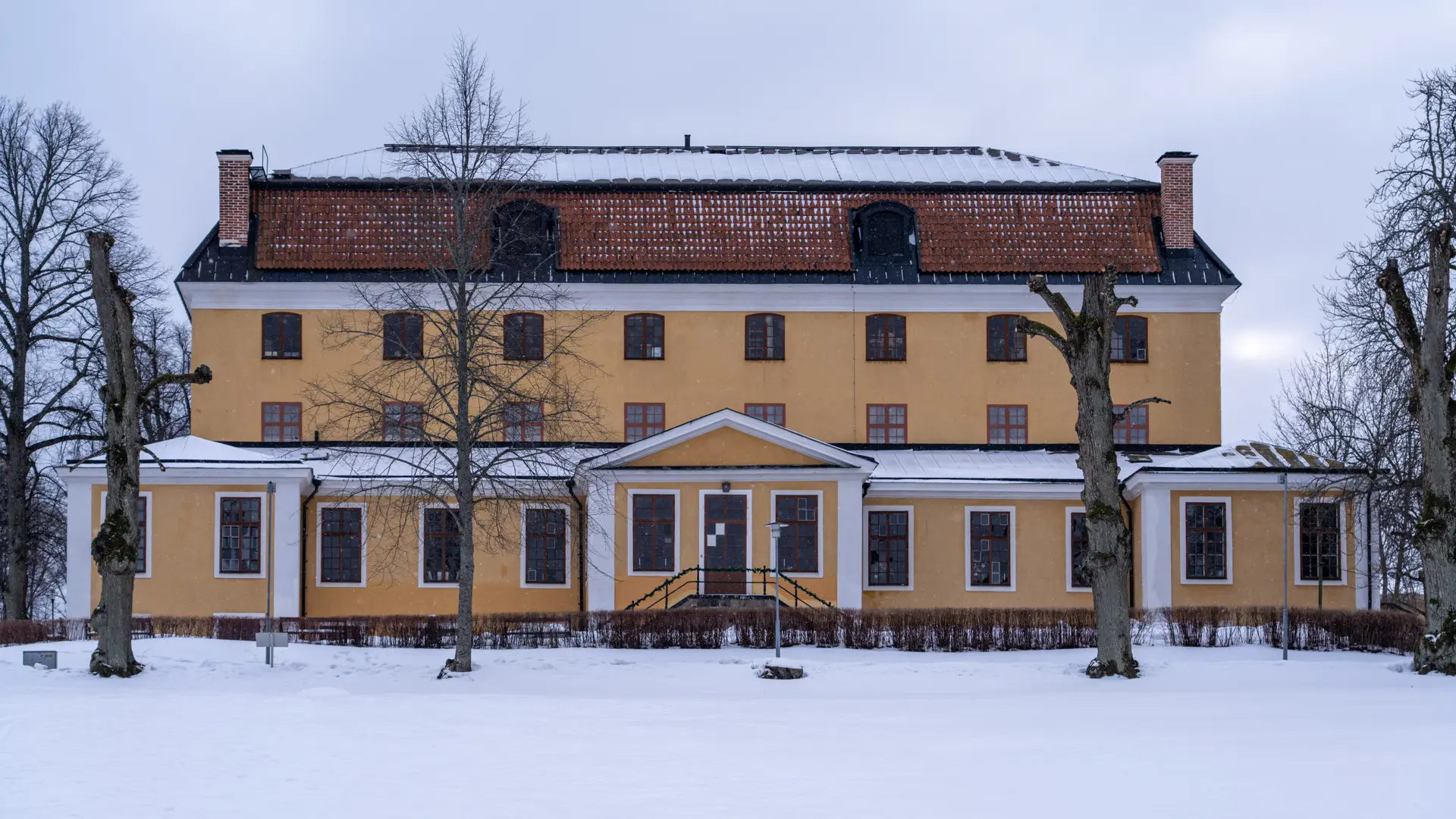 Confidensen vid Ulriksdal. En gul trevåningsbyggnad med brutet tegel-tak. Vinter och snö.