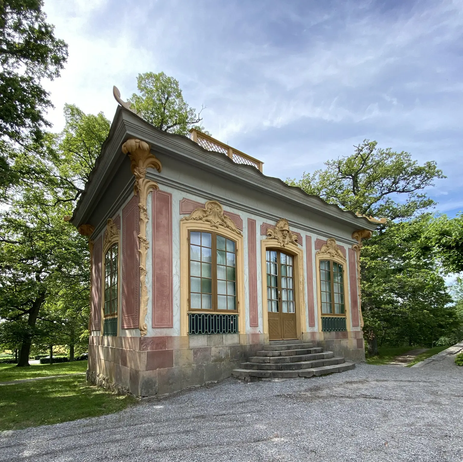 Silverkammaren vid Kina slott, Drottningholm. Liten röd paviljong med gula snickerier. Sommar och grönska.