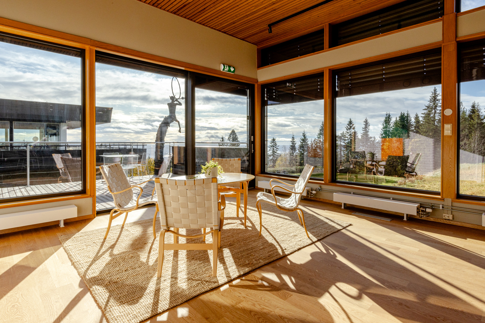 Vardagsrum med stora fönster där solljus flödar in. 