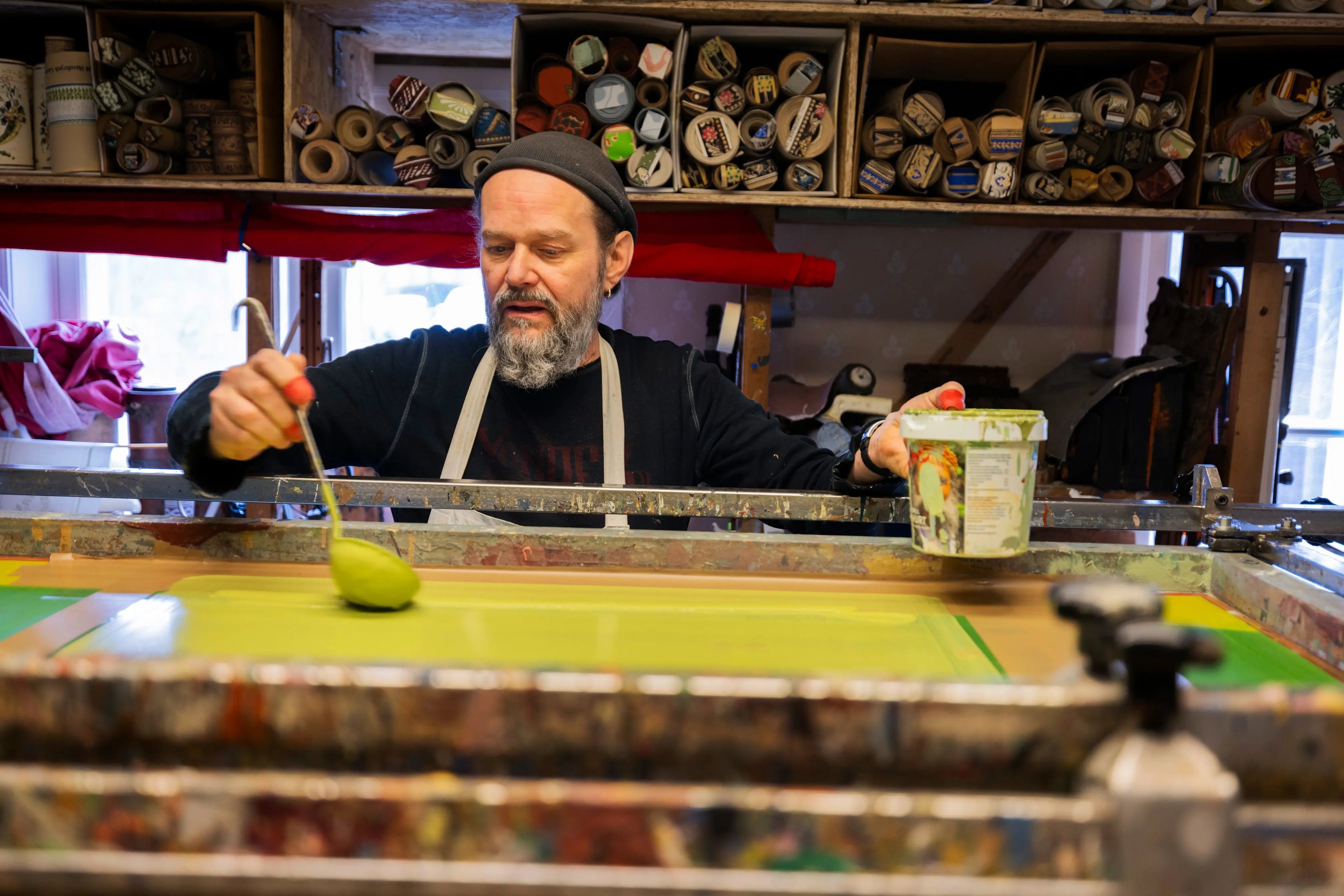 Man häller grön färg i en screentryckapparat.