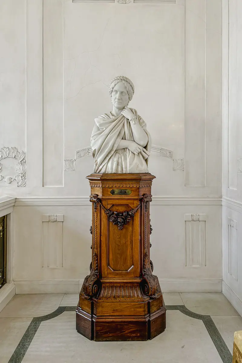 Marmorbyst på en piedestal av mörkt trä.