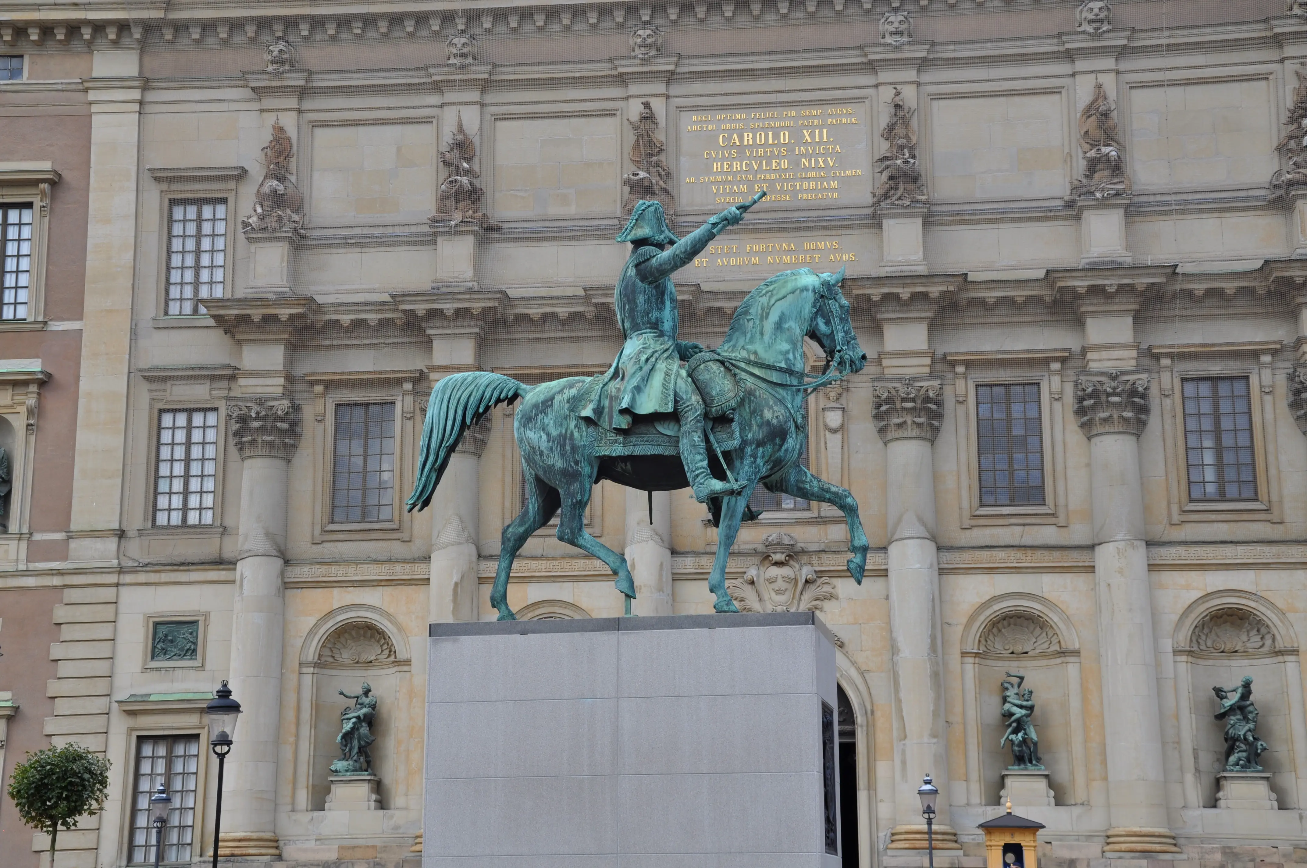 Karl XIV Johans staty på sin tillfälliga plats vid Stockholms slott. En ärgad staty av en ryttare står på en hög stensockel.