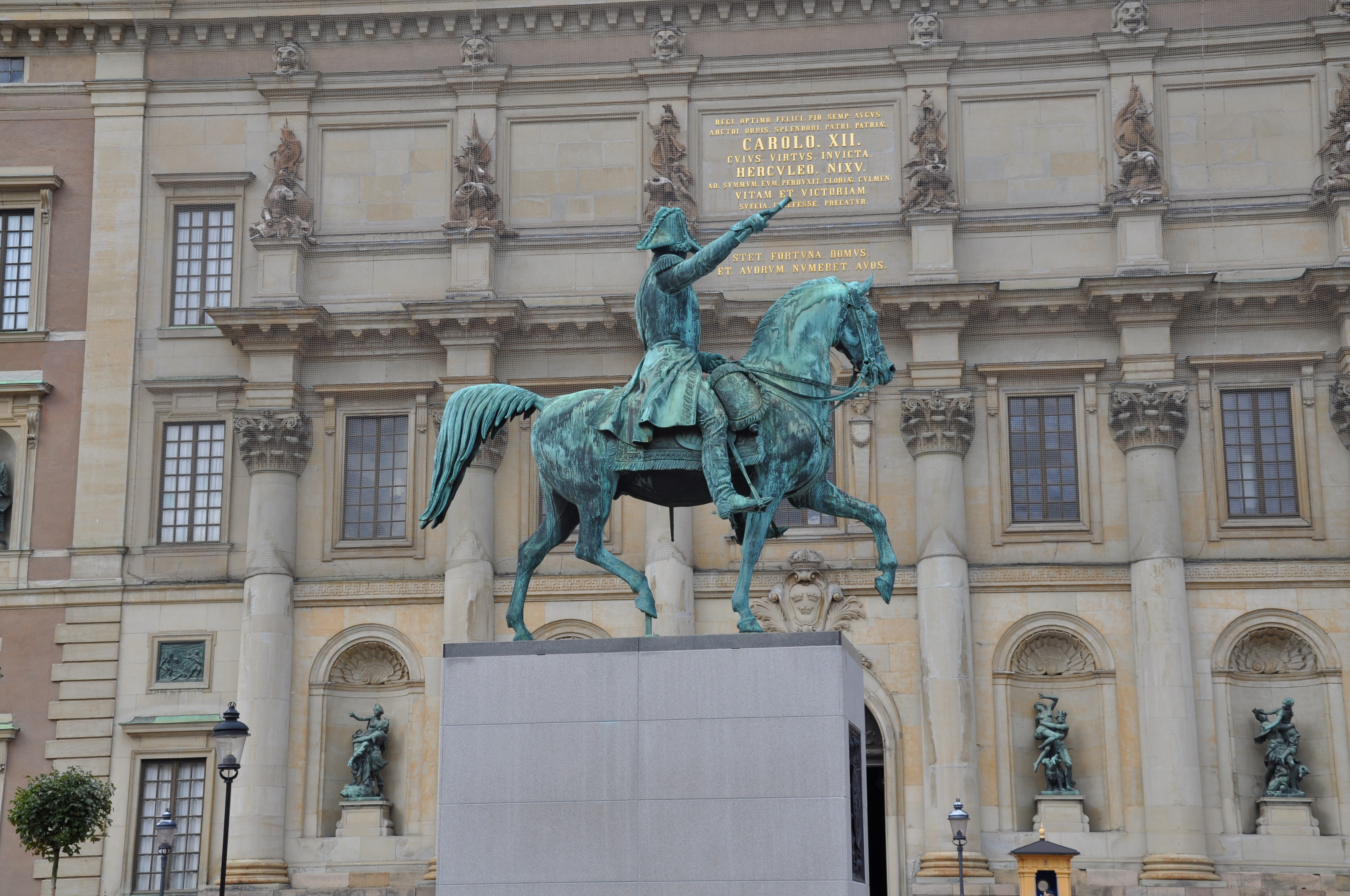 Karl XIV Johans staty på sin tillfälliga plats vid Stockholms slott. En ärgad staty av en ryttare står på en hög stensockel.