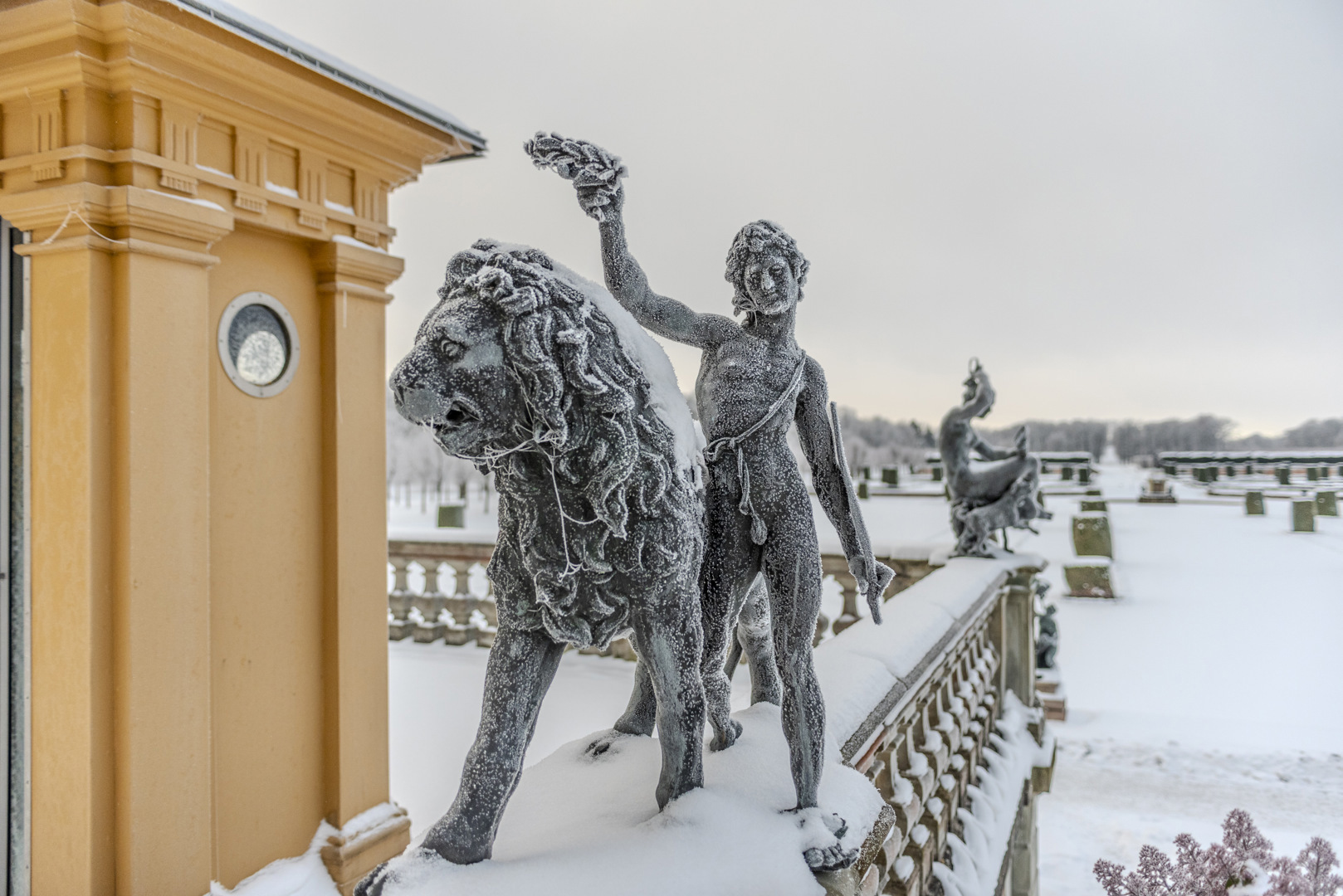 Bronsstatyer täckta av frost. Den närmaste föreställer ett lejon och en person som håller upp en lagerkrans.