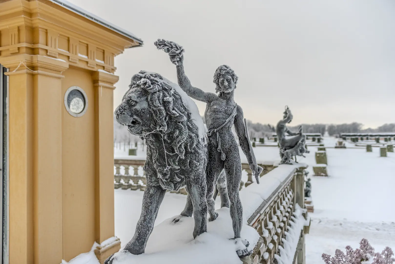 Bronsstatyer täckta av frost. Den närmaste föreställer ett lejon och en person som håller upp en lagerkrans.