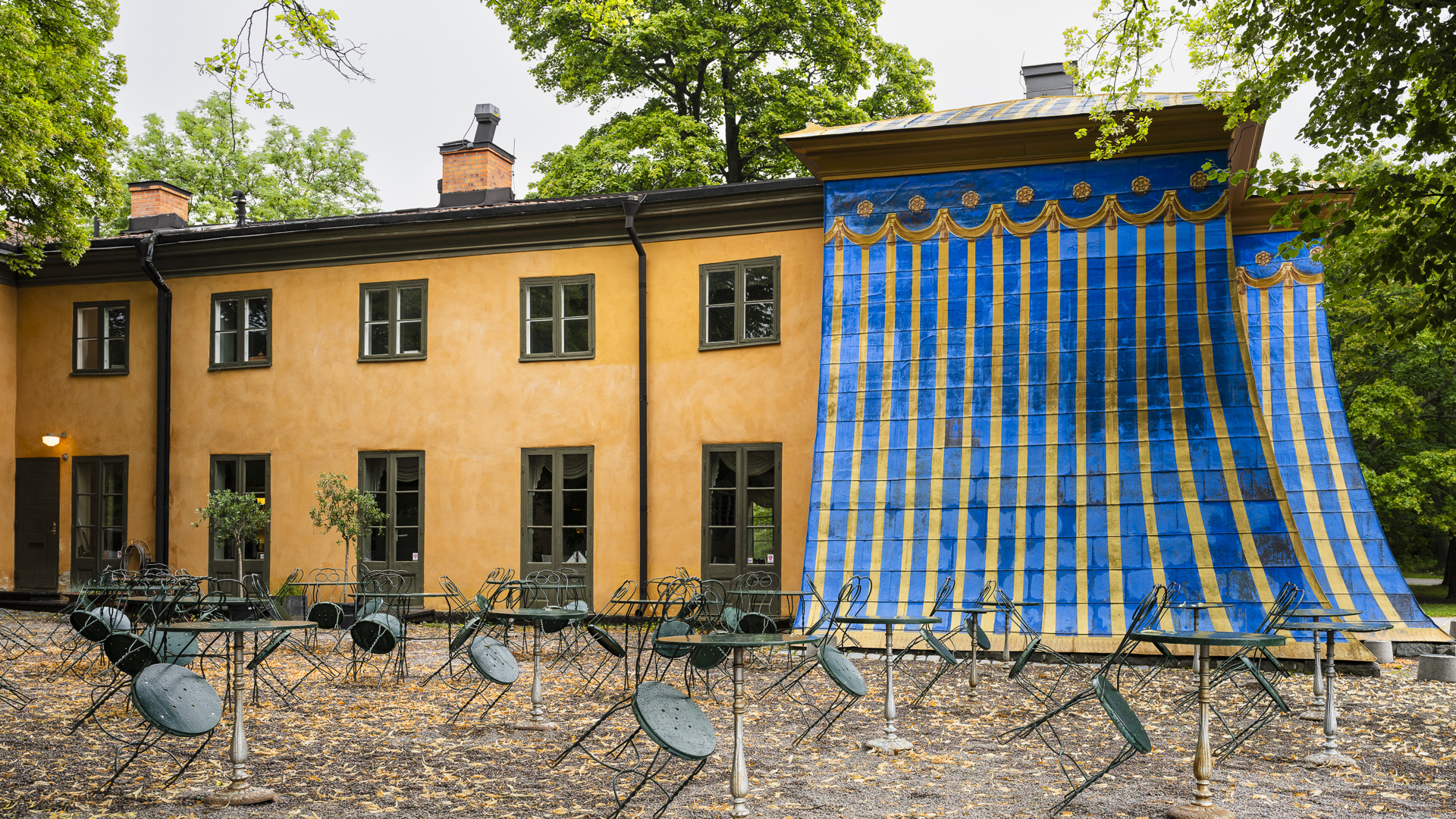Östra koppartältet. En gul byggnad vars ena ände är klädd med kopparplåt målad i blått och guldockra.
