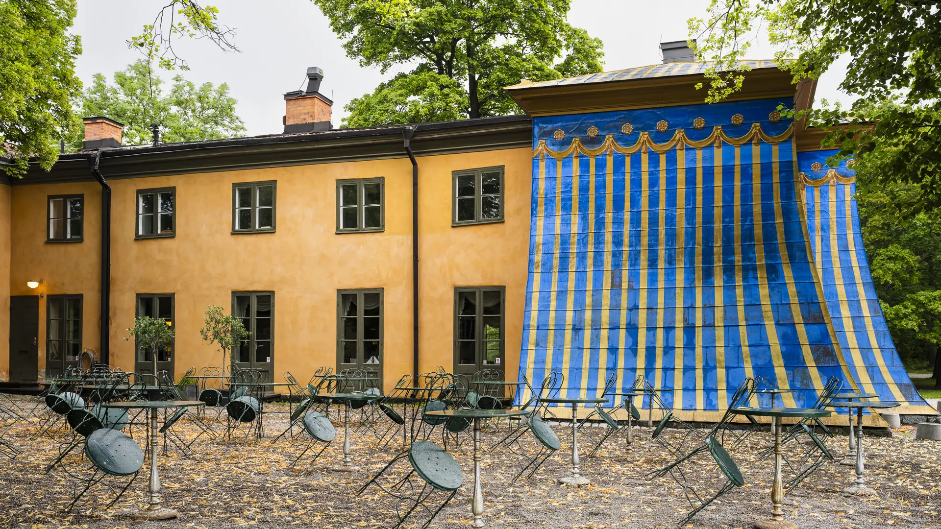 Östra koppartältet. En gul byggnad vars ena ände är klädd med kopparplåt målad i blått och guldockra.