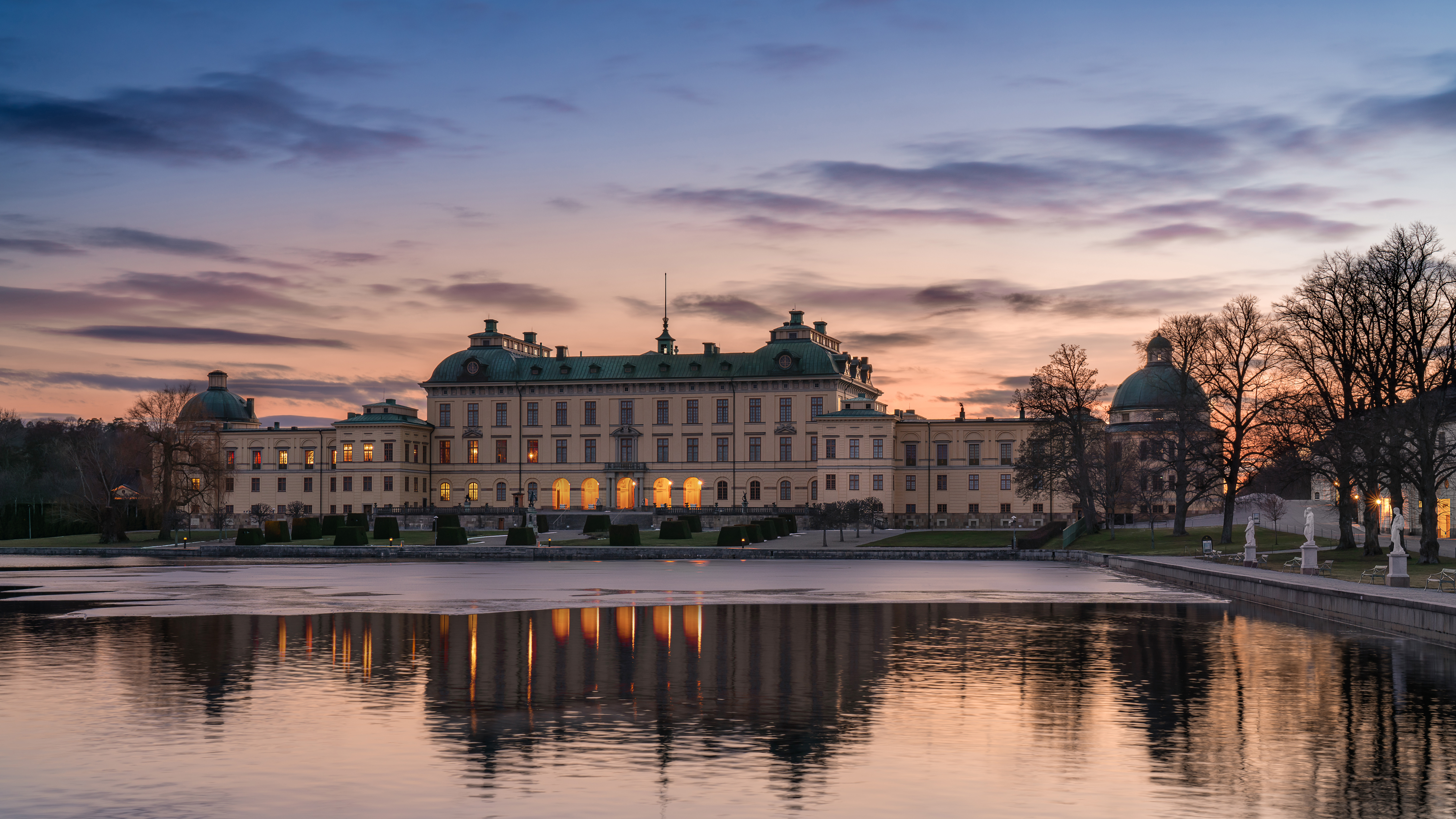 Drottningholms slott i kvälls-ljus, sett över vattnet från Kärsön. Vinter och is.