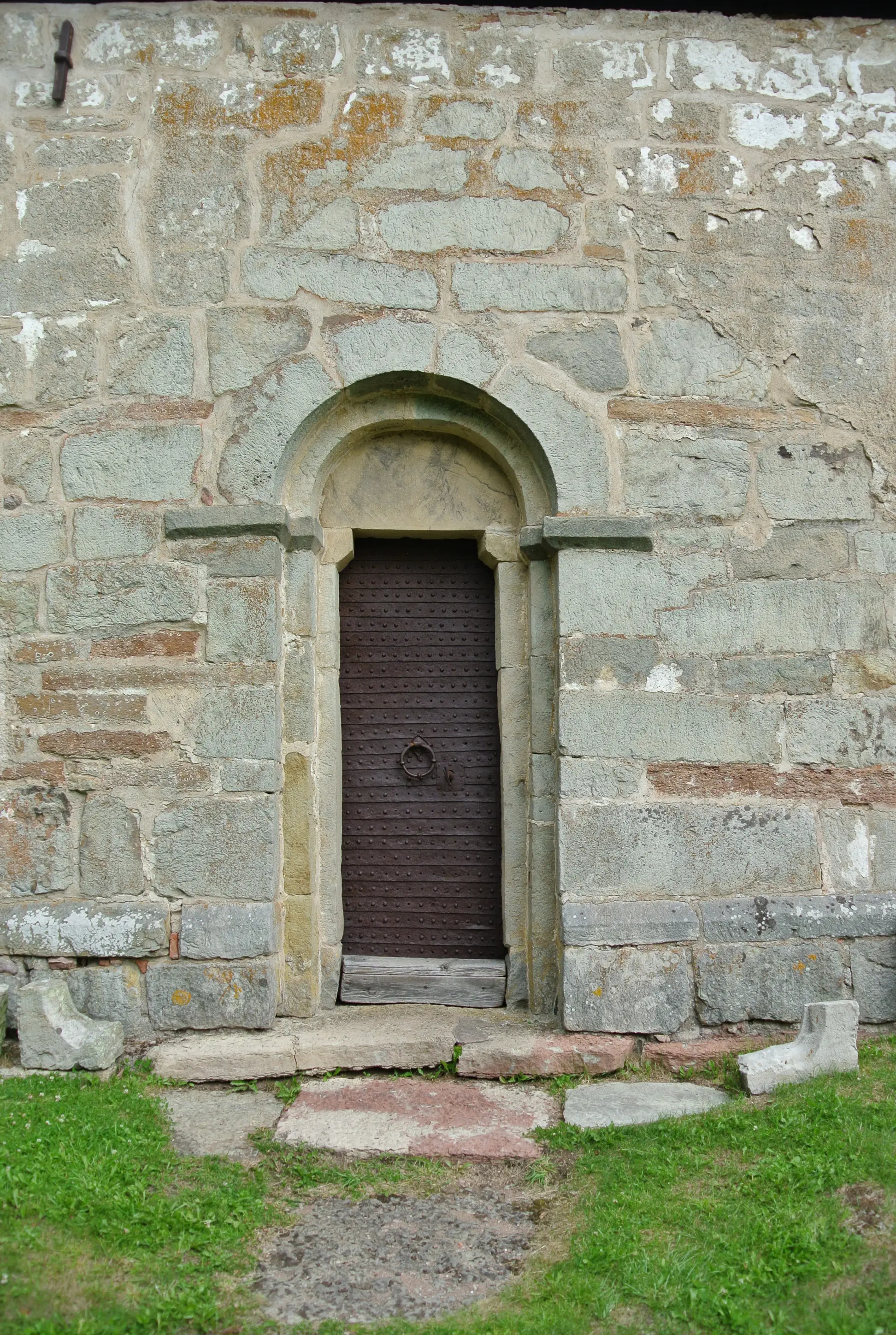 Suntaks gamla kyrka. Rundad, medeltida stenportal. Dörren är klädd i järn och har en rund portklapp i smide.
