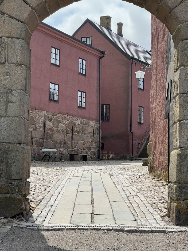 Stenvalv med två rosaputsade fasader i fokus.