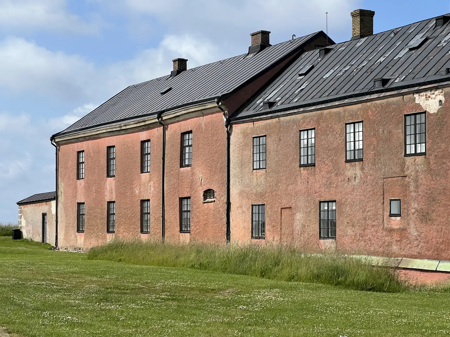 Rosaputsad fasad med spröjsade fönster.