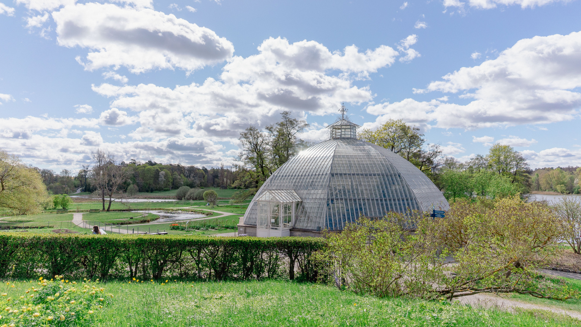 Bergianska trädgården, vår. Utsikt över parkens gräsytor och gångvägar. I förgrunden Victoria-växthuset.