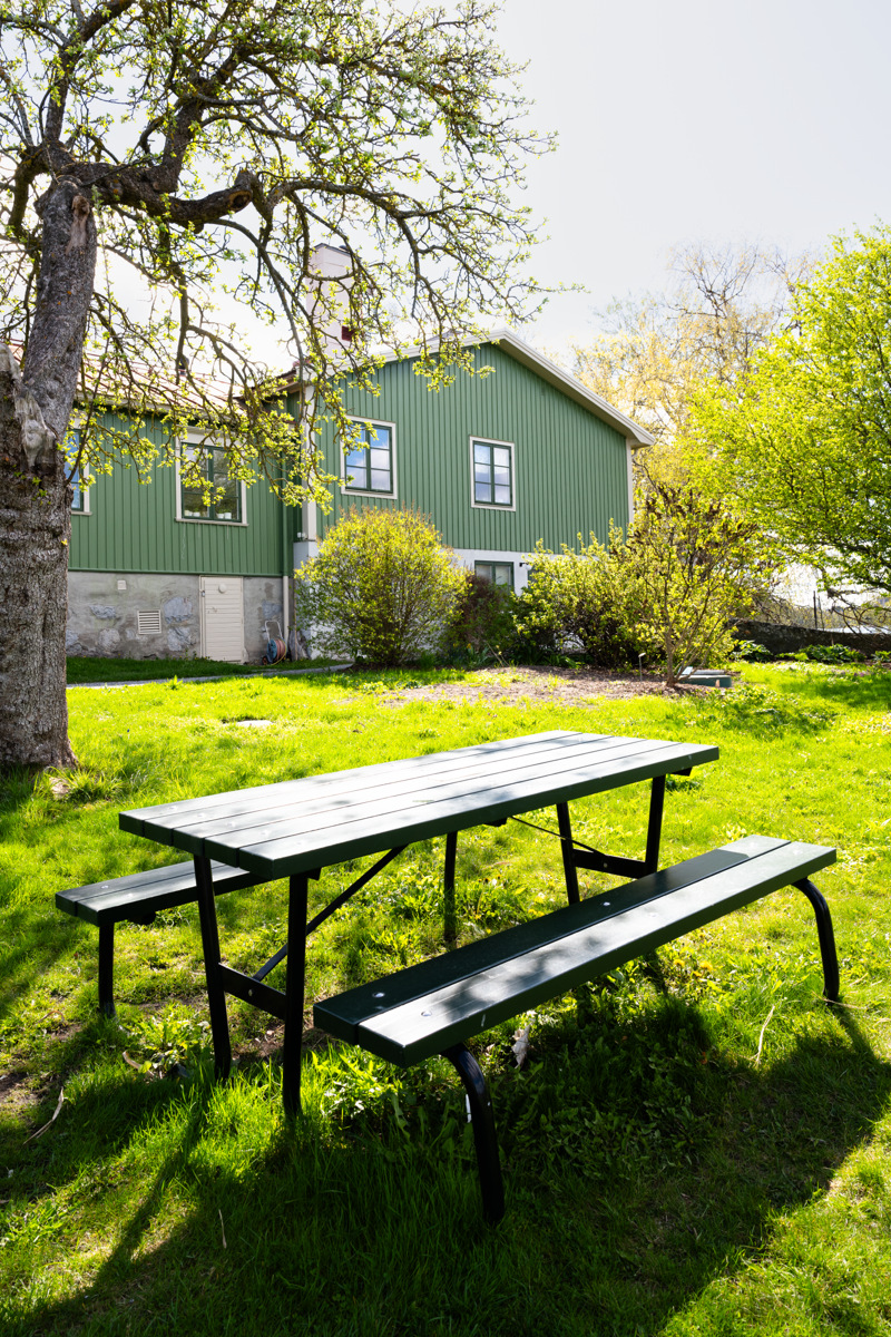 Bergianska trädgården. Grönt trähus. Framför huset står ett bänkbord på en gräsmatta.