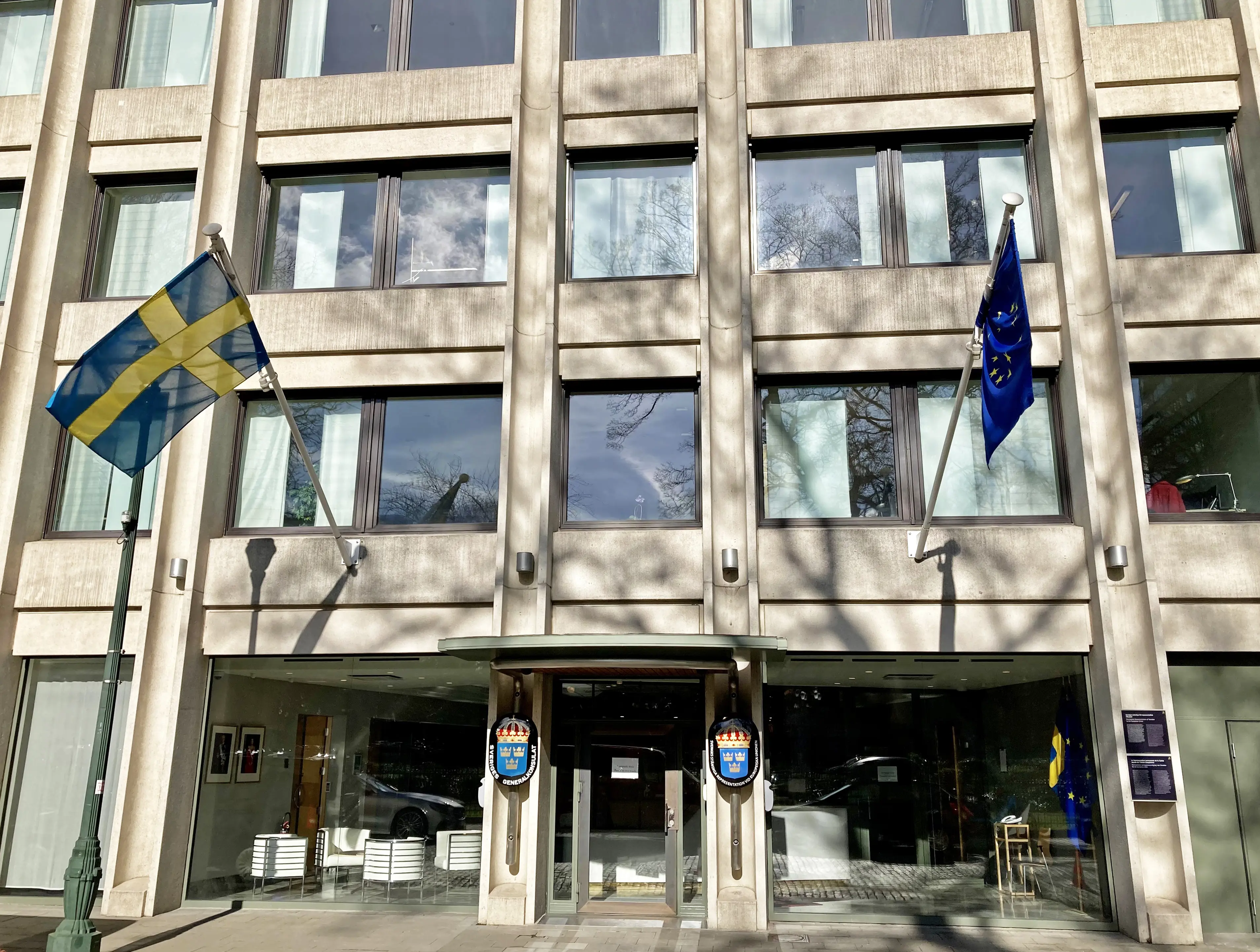 Bryssel, Sveriges ständiga representation vid EU. Kontorsbyggnad i betong, med stora fönster. Från fasaden vajar Sveriges respektive EU:s flagga.