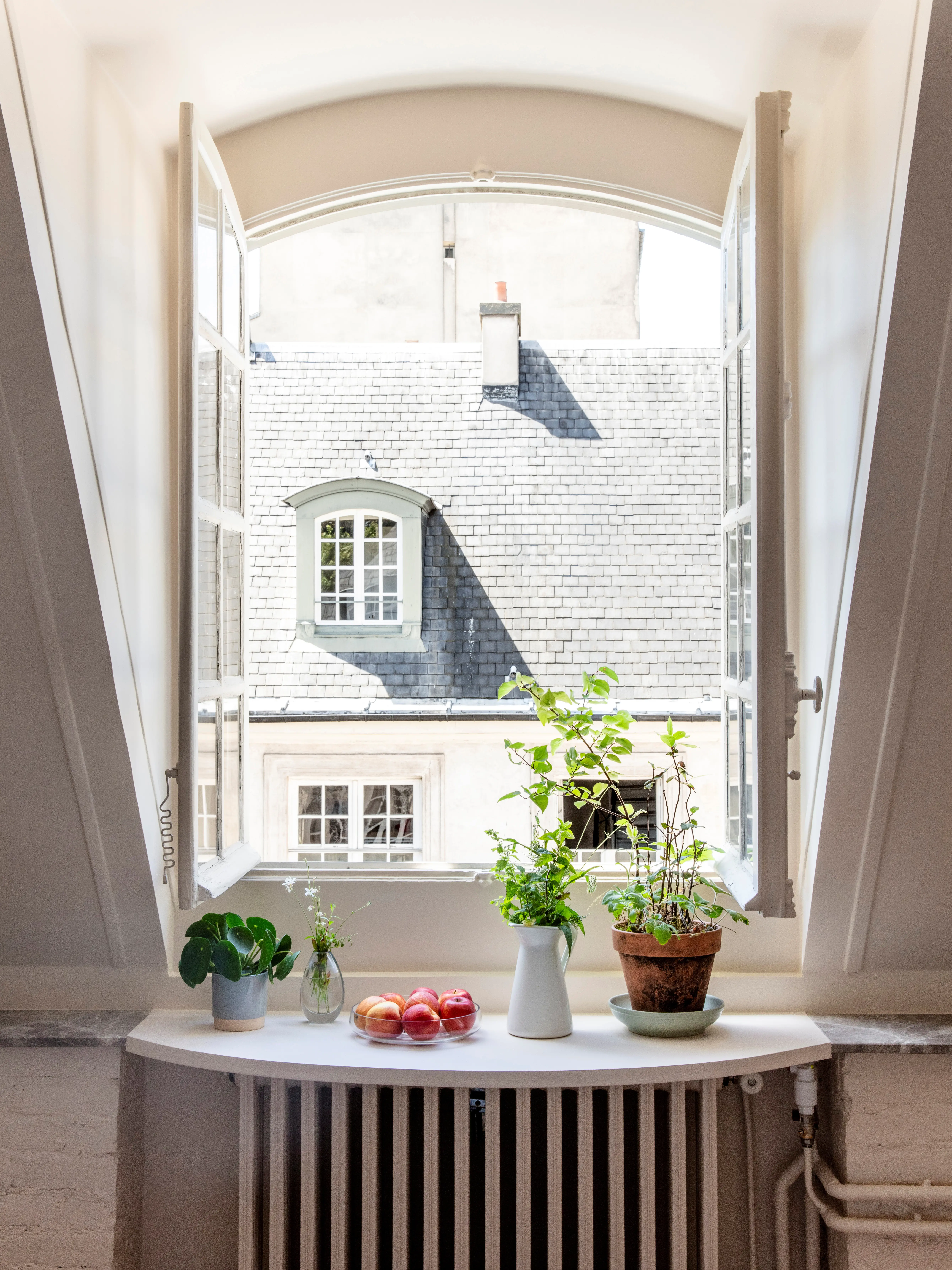 Svenska institutet i Paris. Gästbostad. Utsikt genom ett stort, öppet fönster mot ett hustak med tak-kupa.