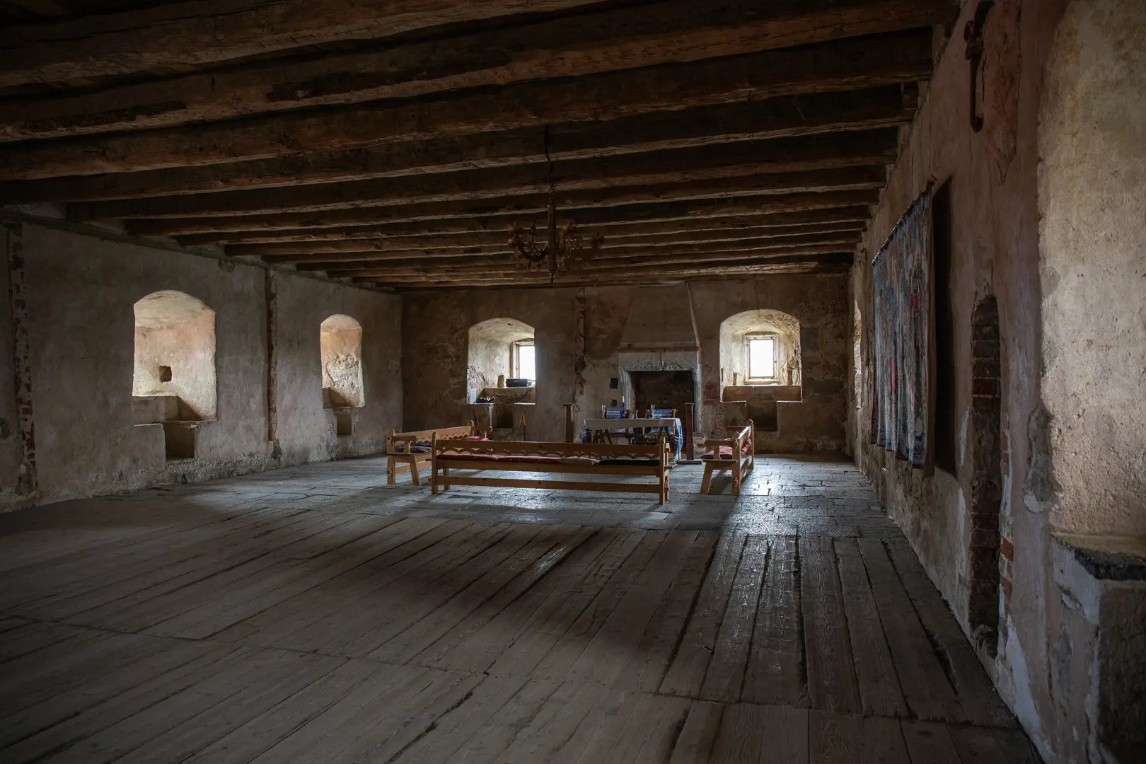 Ett stort rum med trägolv och träbjälkar och ljuskrona i taket.