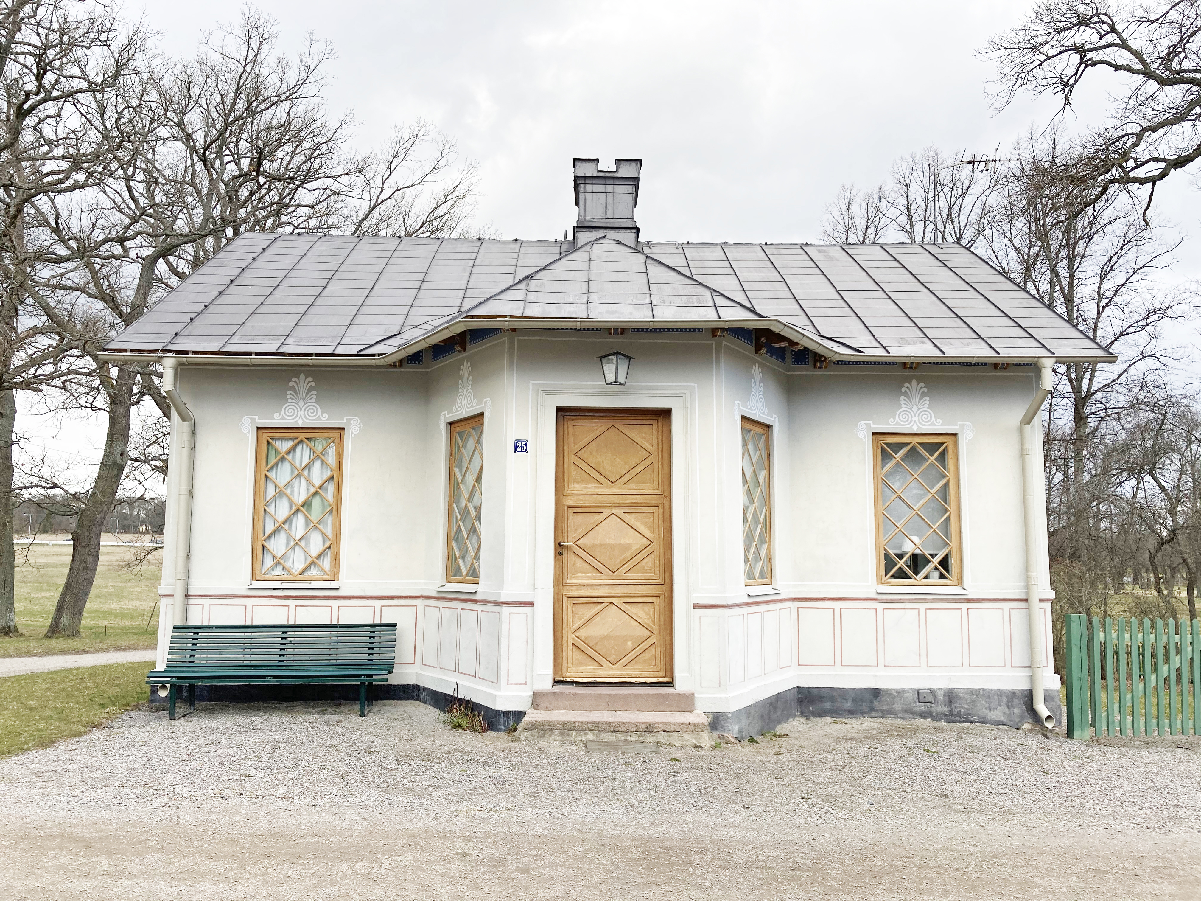 Grindstugan, Drottningholm. Ett vitt litet hus med dekorativ fasadmålning. Fönstren har diagonal spröjs och trädörren har diagonala speglar.