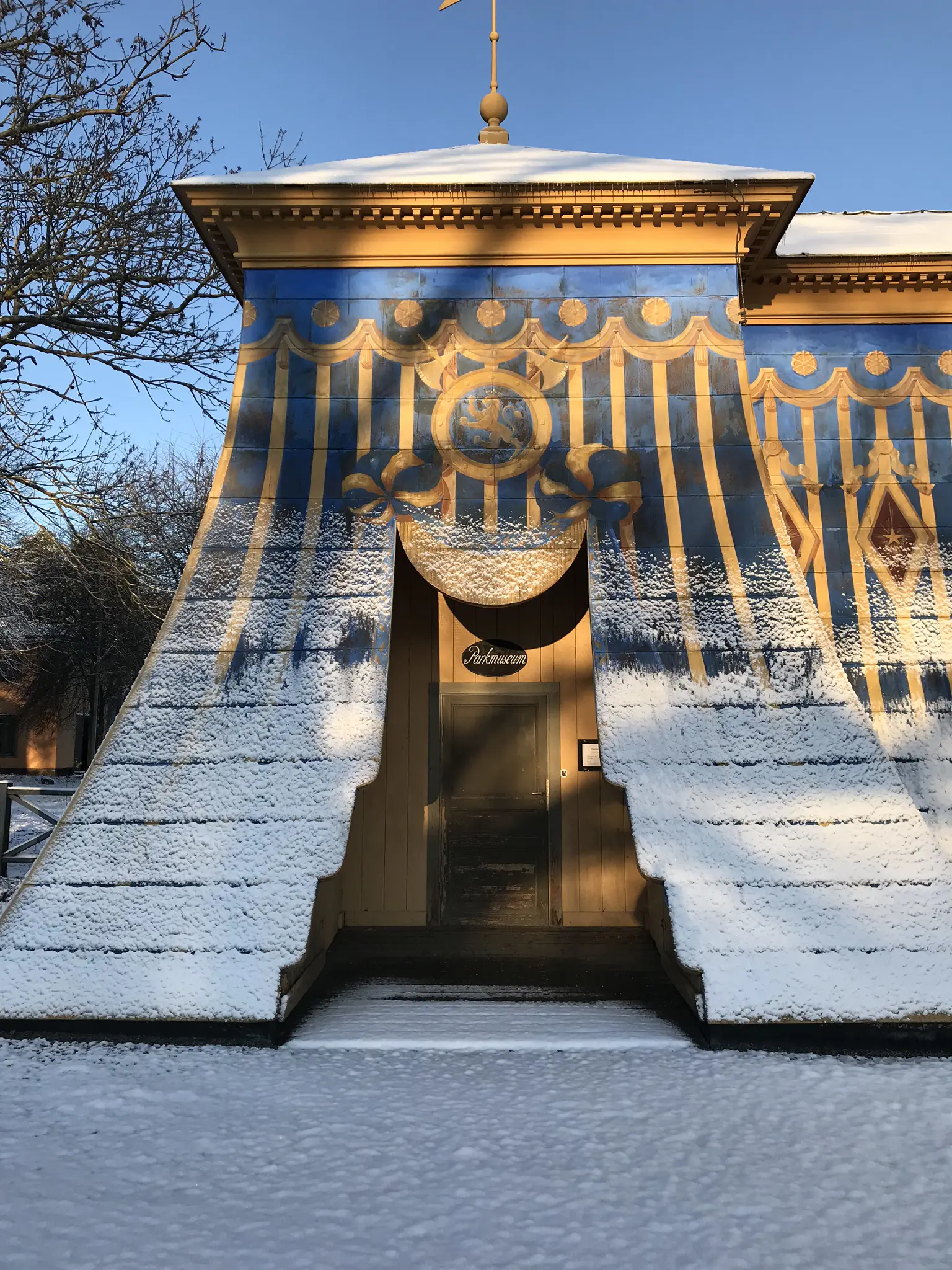 Mellersta koppartältet i Hagaparken. Entrén till Haga parkmuseum, genom en enkel trädörr. Vinter, snö och sol.