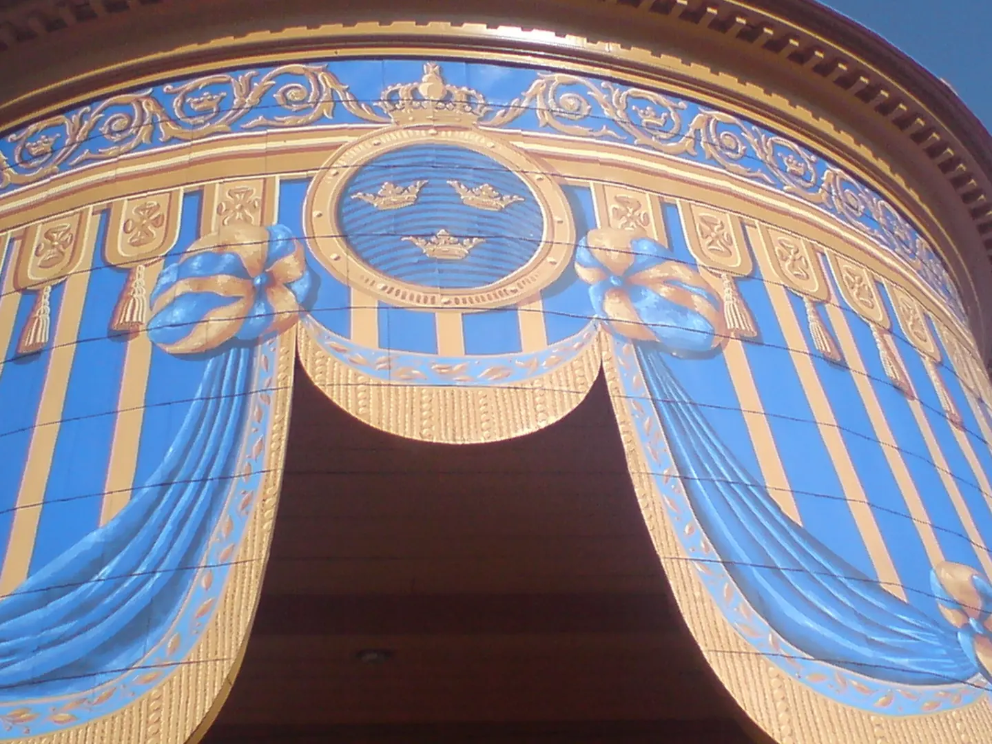 Närbild av entrén till mellersta koppartältet, målad som om en öppning i en tältduk. Överst syns tre kronor.