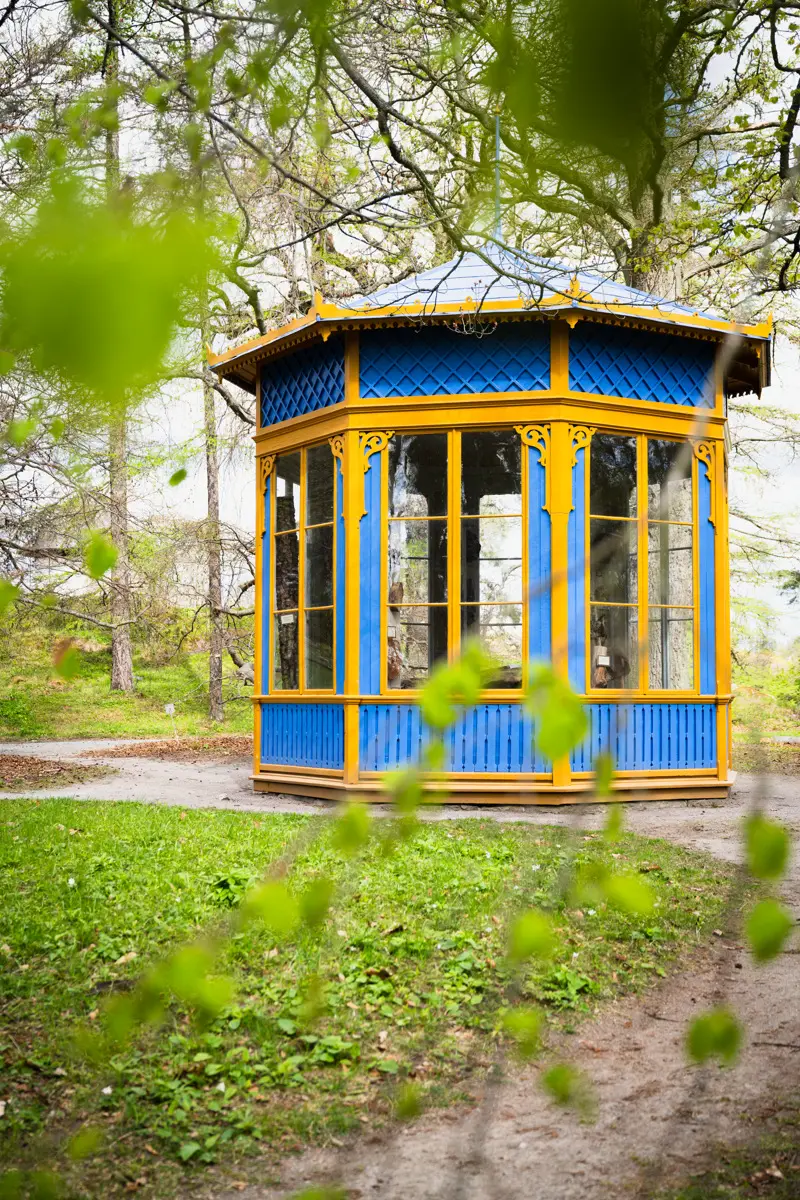 Bergianska trädgården. Trädgårdspaviljong med stora fönster. Fasaden är blå, med gula snickerier.