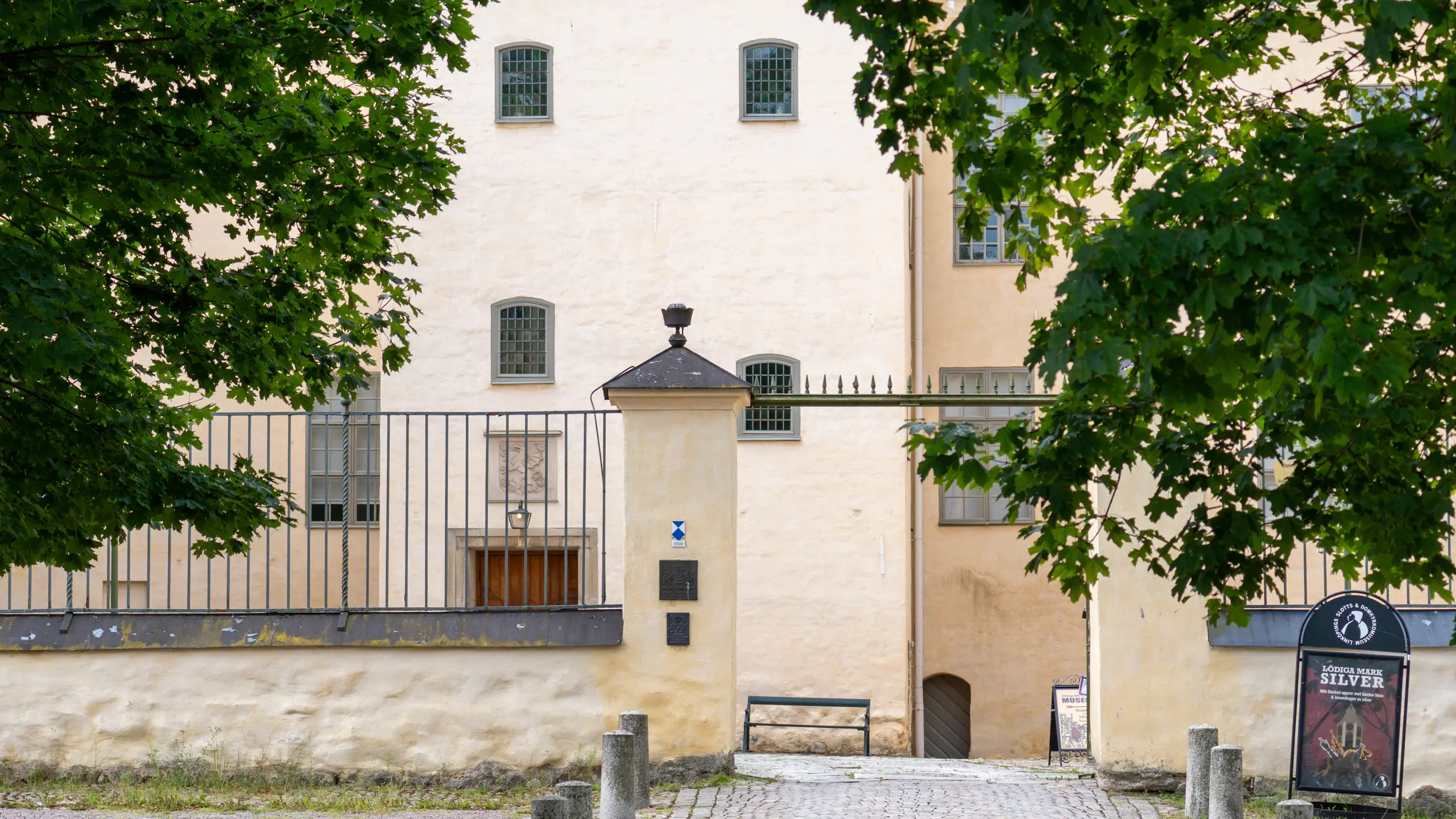 Linköpings slott. Fasaden är putsad blekt orange. Runt borg-gården går en låg mur med staket på.