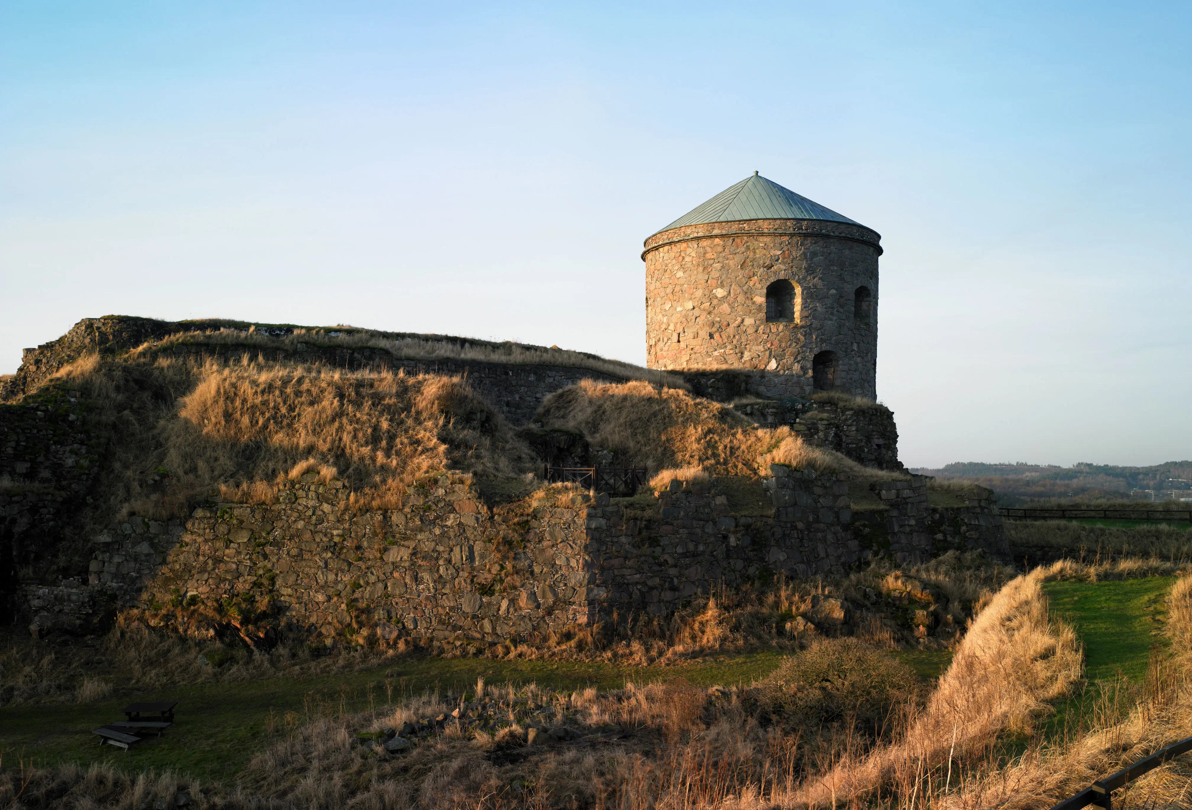Solbelyst stenborg, delvis i ruiner med ljustblå himmel.