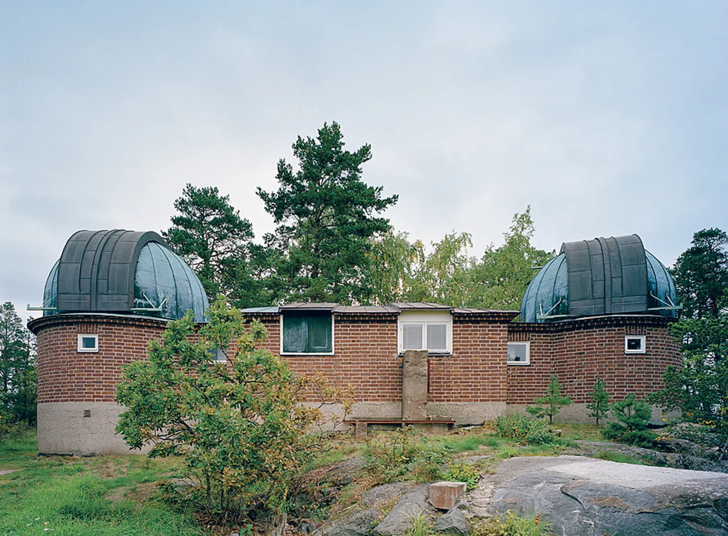 Observatoriet sett utifrån. Låg tegelbyggnad med rundade hörn försedda med takkupoler.