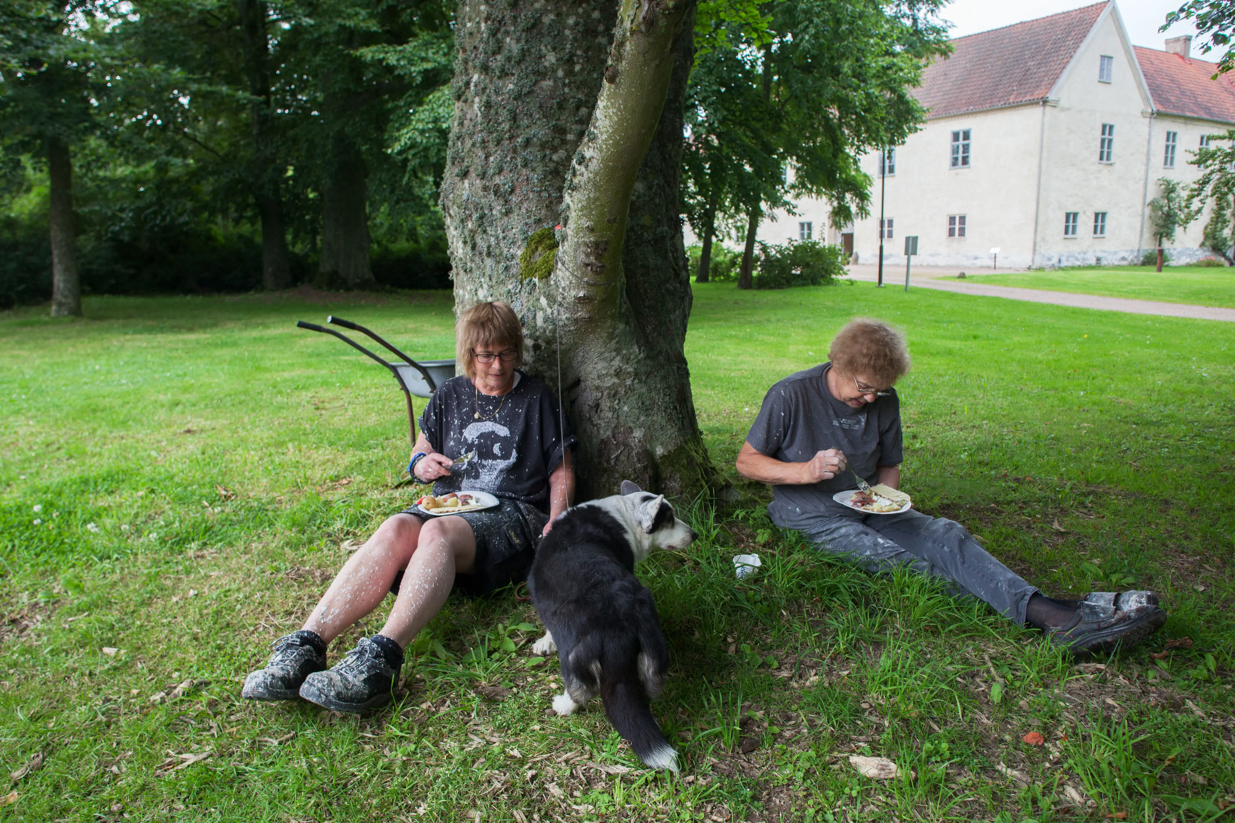 Lena Lindqvist, hunden Agnes och Gudrun Svensson äter lunch under ett träd.