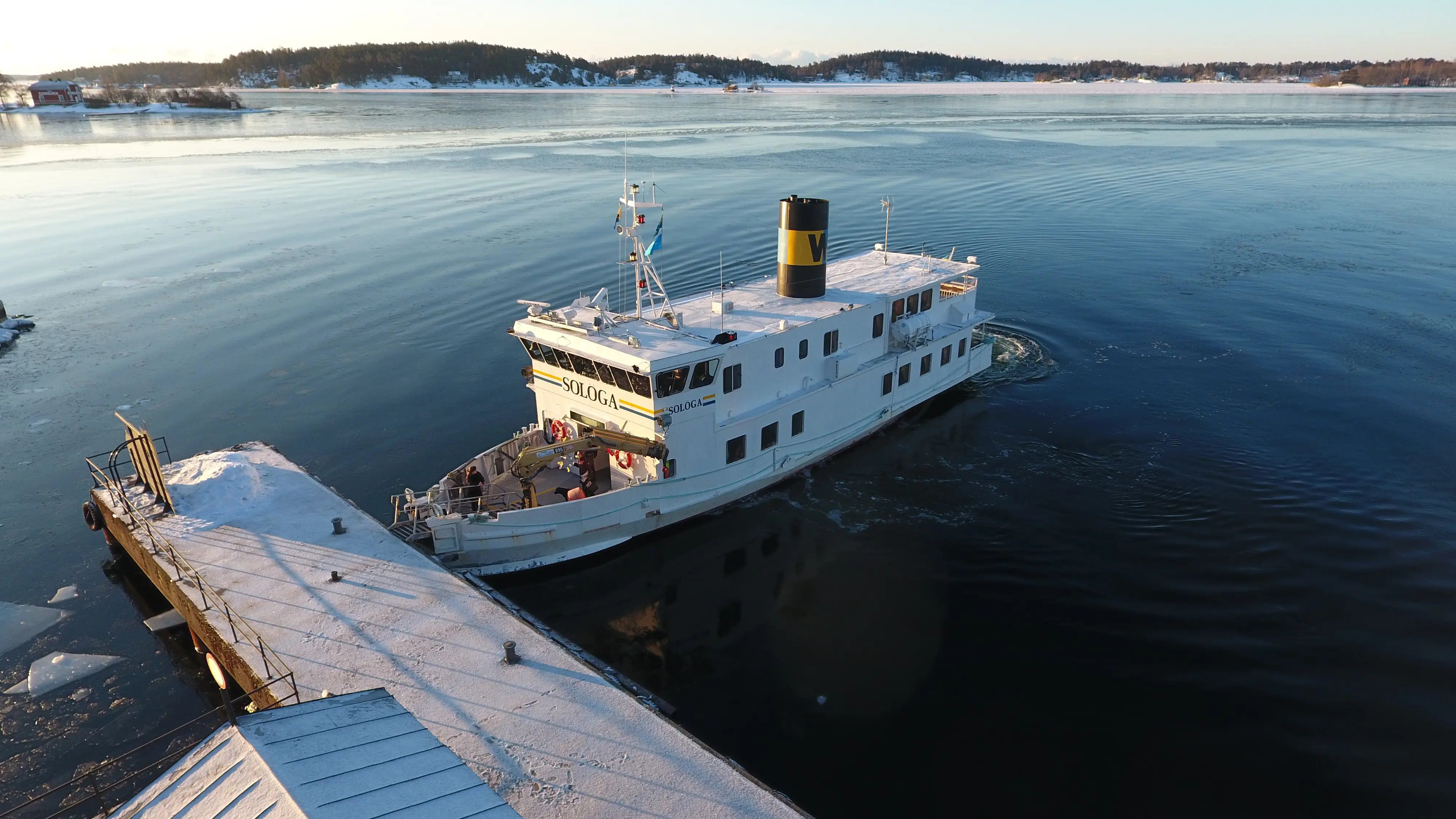 Vaxholms kastell. Färjan Solöga lägger till vid bryggan. Vinter och snö. Vattnet på fjärden är delvis istäckt.