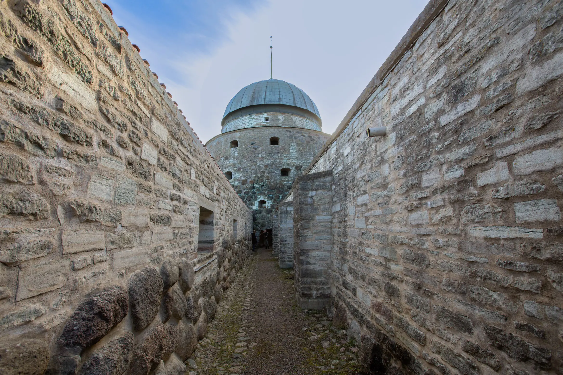 Kullerstens- och grusgång omgiven av stenmurar leder mot ett av slottets torn