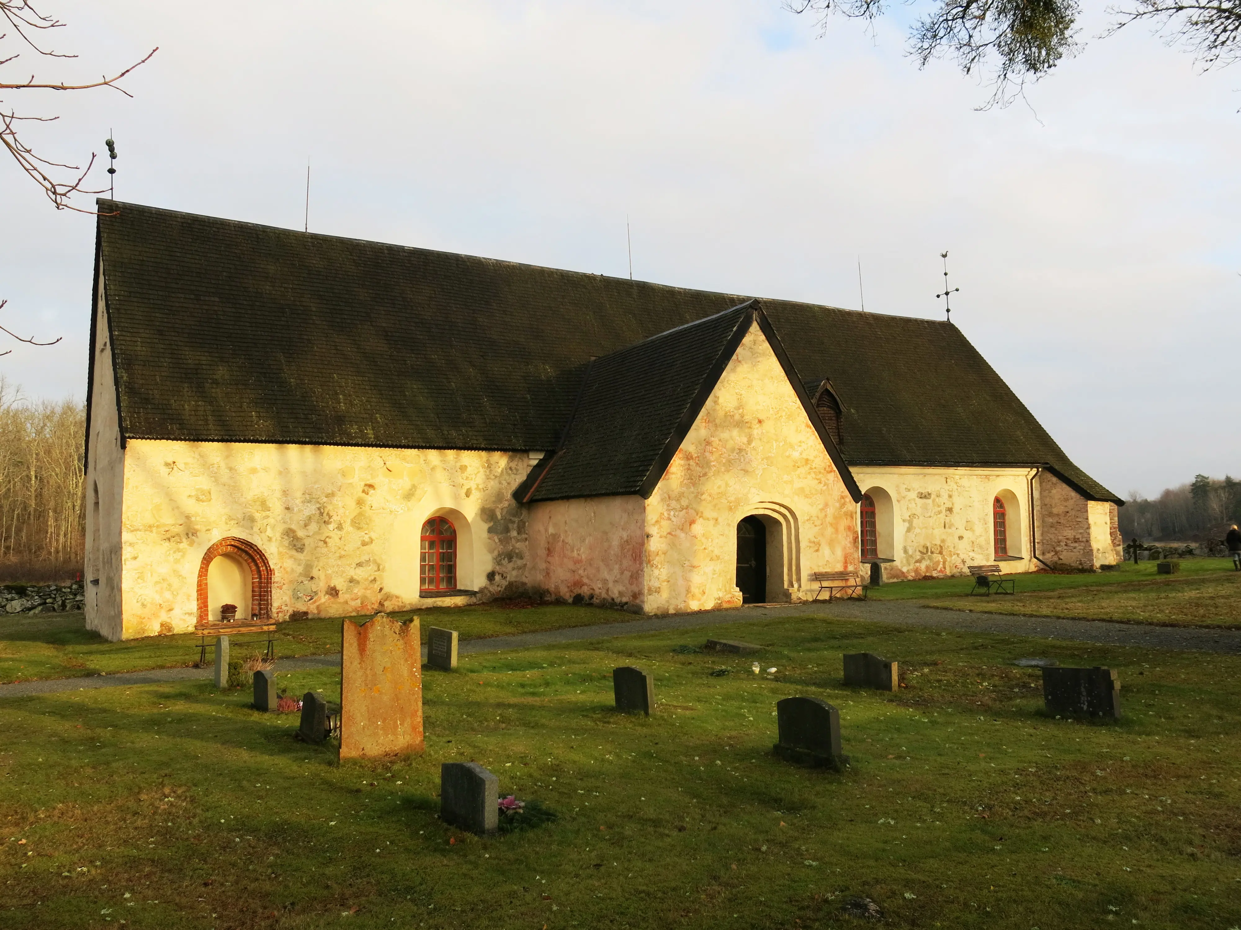 Arnö kyrka. En långsträckt, vitputsad byggnad med brant, tjärat spåntak och rundbågiga fönster.