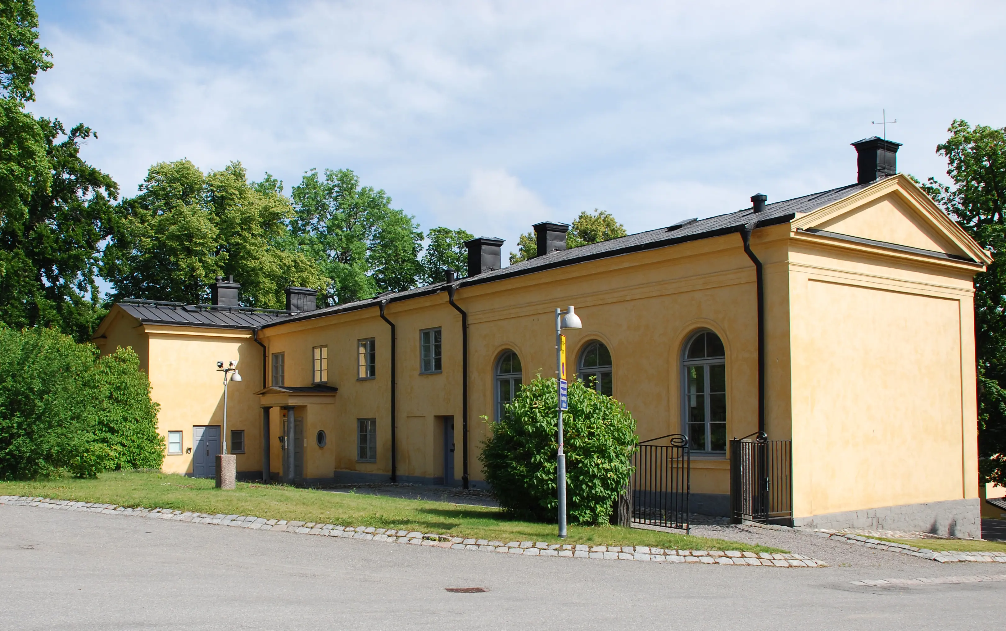 Prästgården, Skeppsholmen. En gulputsad tvåvåningsbyggnad inramad av grönskande träd.