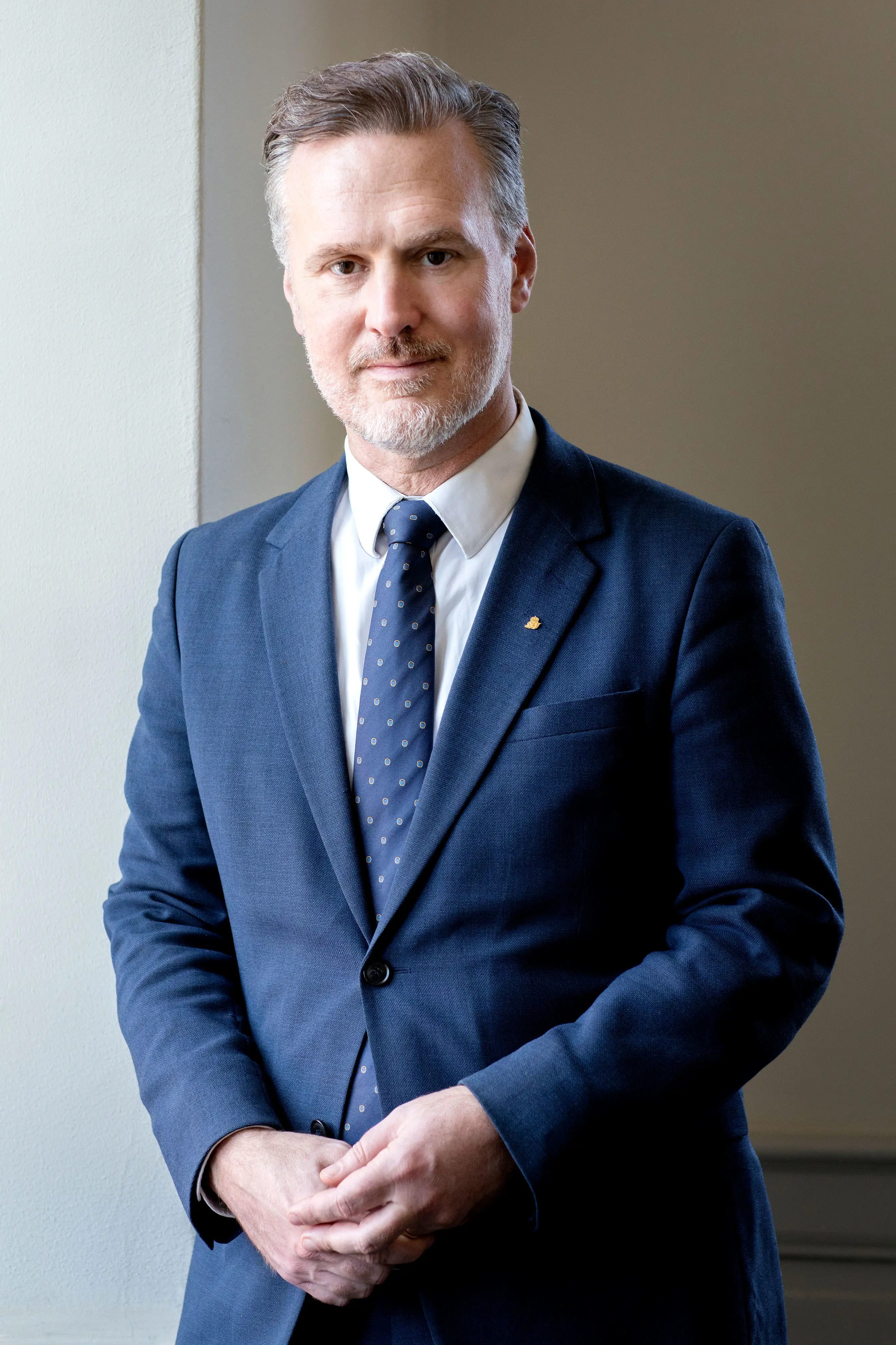 Generaldirektör Max Elger stående mot en vägg iklädd blå kostym, vit skjorta och prickig slips.