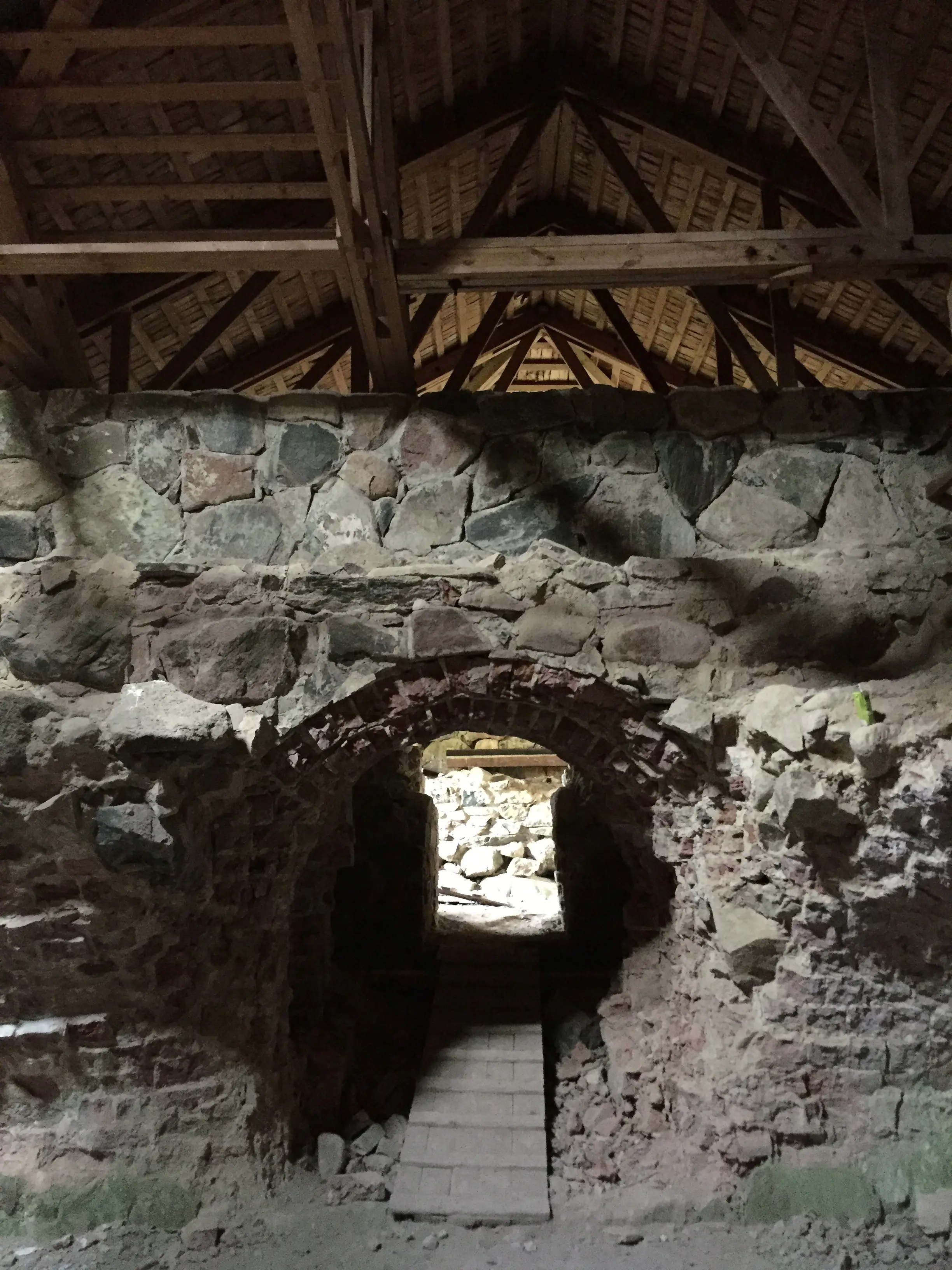 Interiör, Kägleholms slottsruin. En massiv stenvägg är någorlunda intakt. En träramp leder genom en dörröppning.