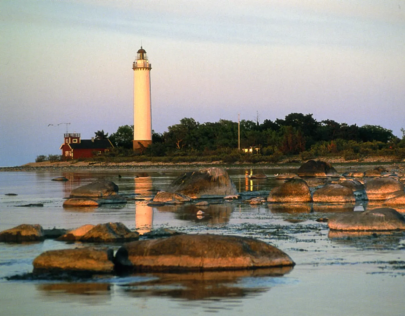 Fyren Långe Erik med en förgrund av solbelysta stenar i vattnet.