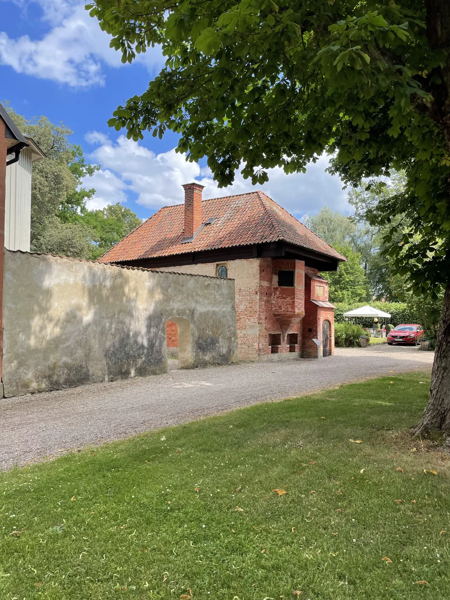 Mårten Skinnares hus. Litet rödputsat tvåvåningshus med brant tegeltak. En mur förbinder huset med Hospitalsmuseet. Sommar och grönska.