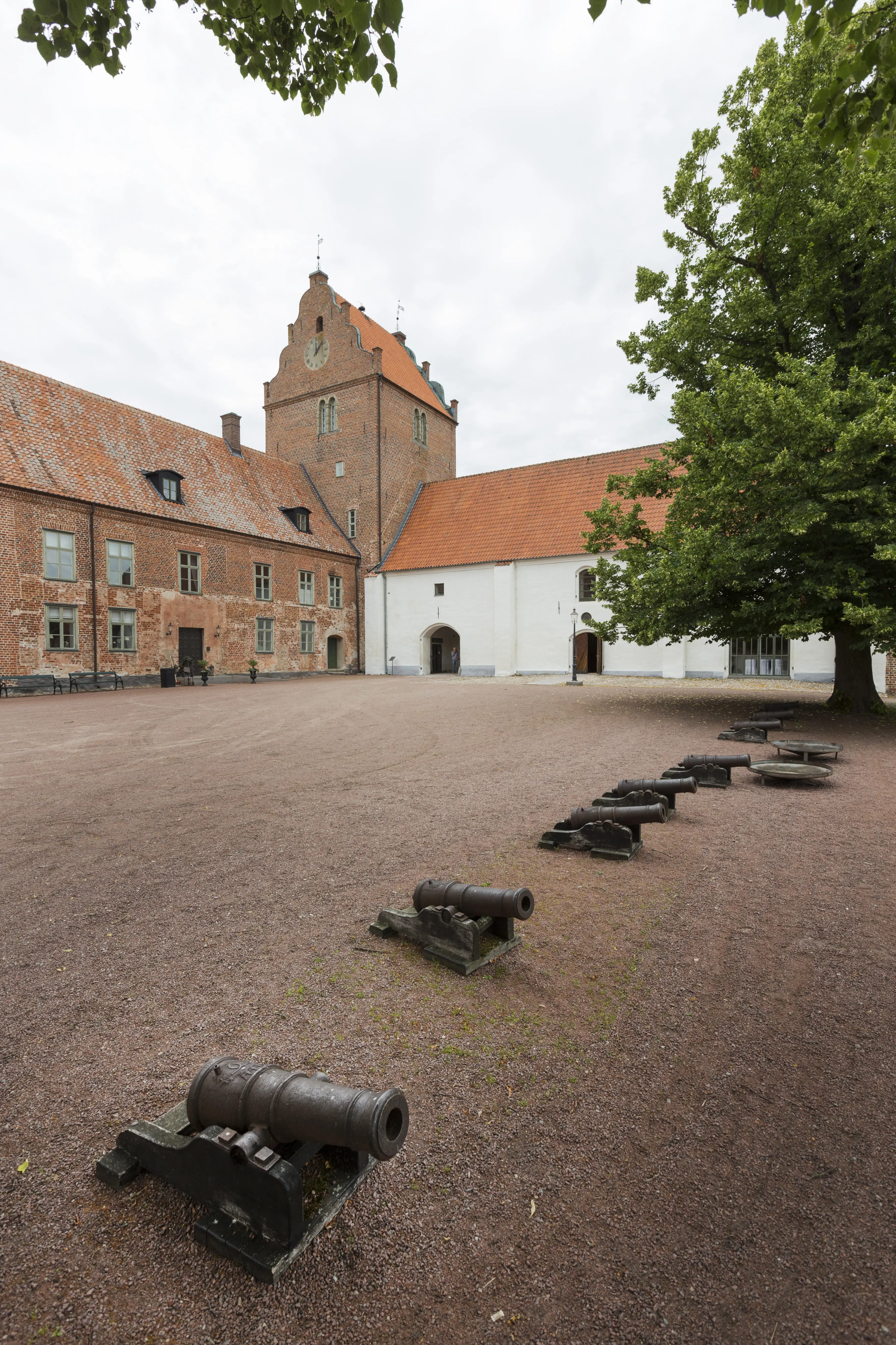 Borggården på Bäckaskogs slott. En grus-plan med en rad kanoner.