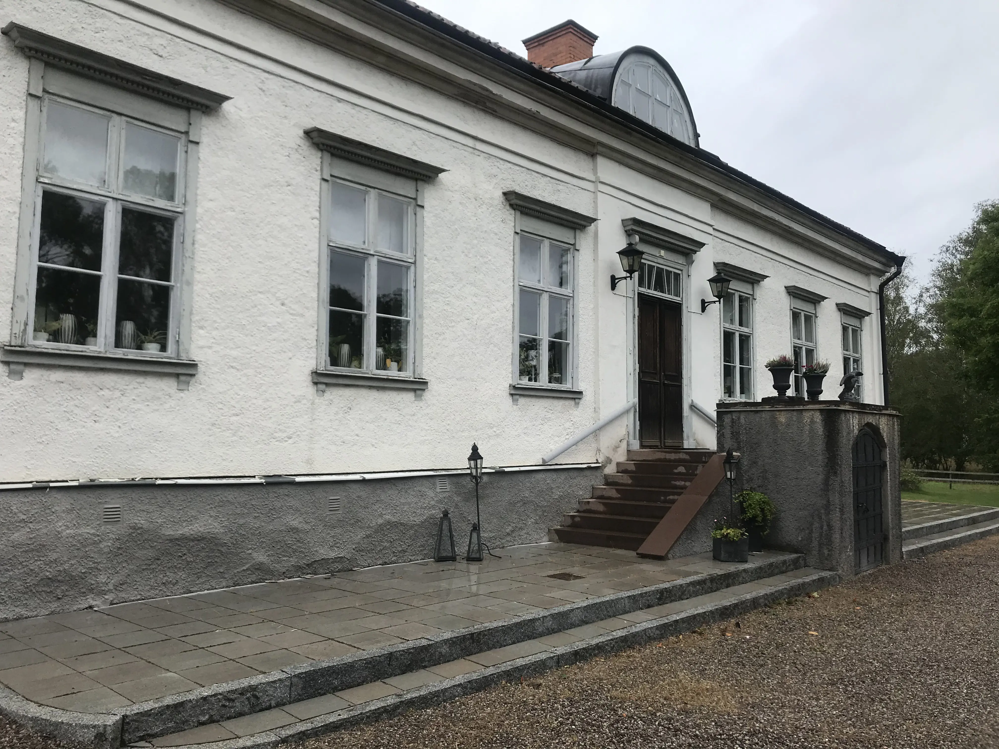 Mangårdsbyggnaden på Herrsäter. En vitputsad envåningsbyggnad med halvmåneformad tak-kupa.