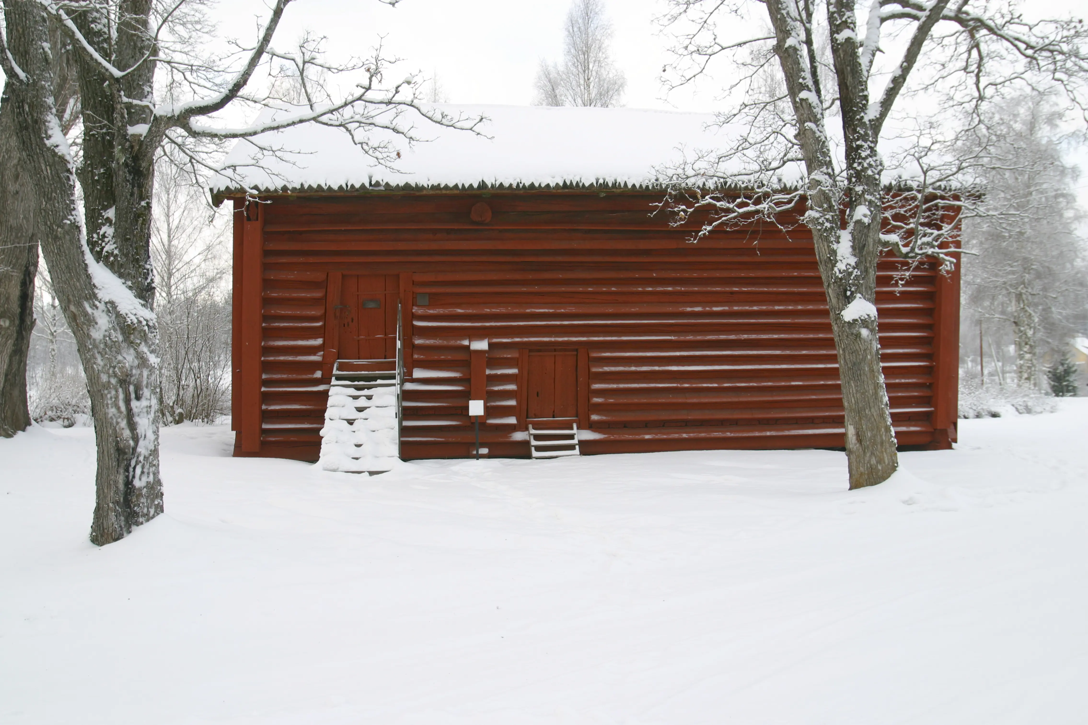Rankhyttan. Liten timrad, faluröd stuga inbäddad i snö.