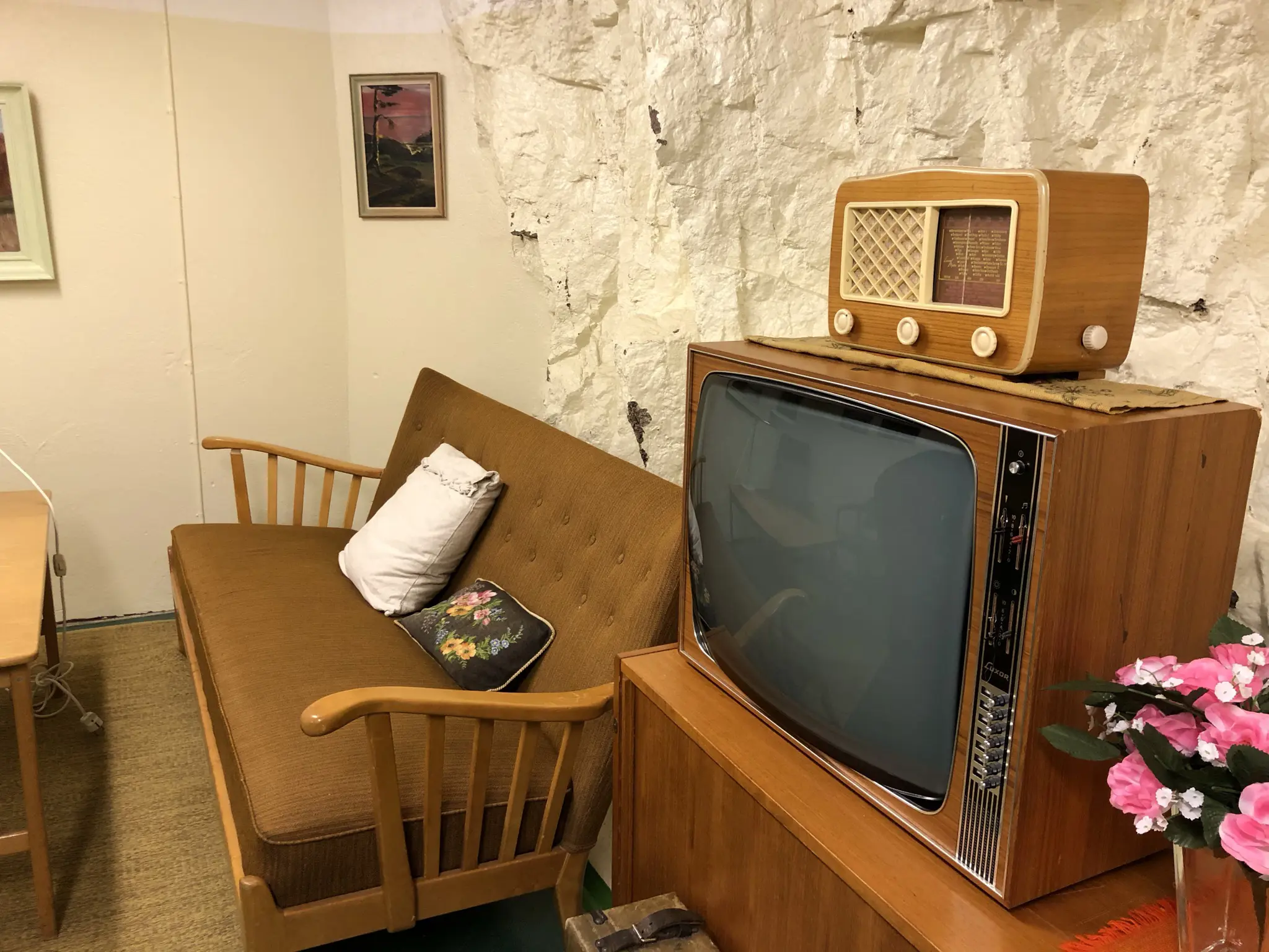 Bodens fästning. Inredning från 1960-talet. Bredvid en träsoffa med brun ylleklädsel står en teve och en radio med träfanér.