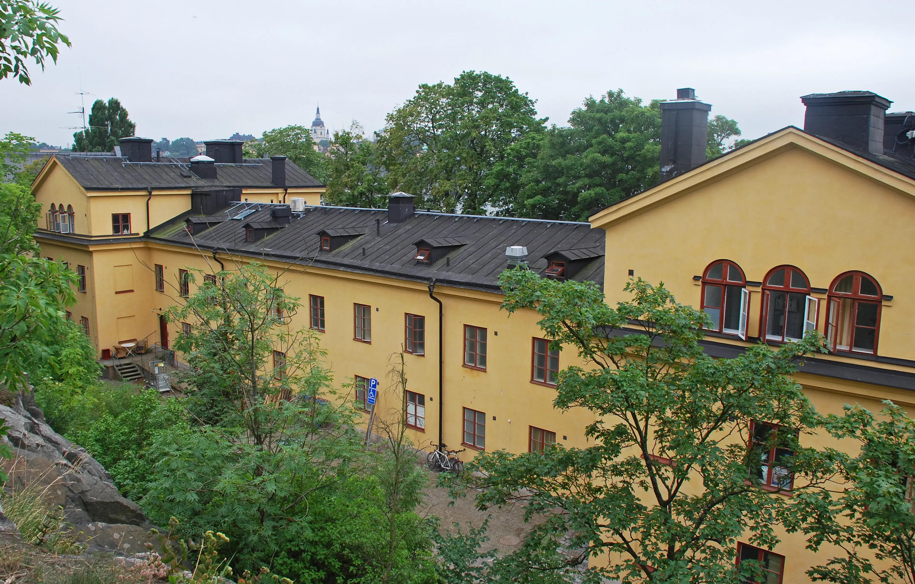 Hantverkskasernen på Skeppsholmen. En gulputsad klassicistisk byggnad i två våningar, med flyglar som är en våning högre.