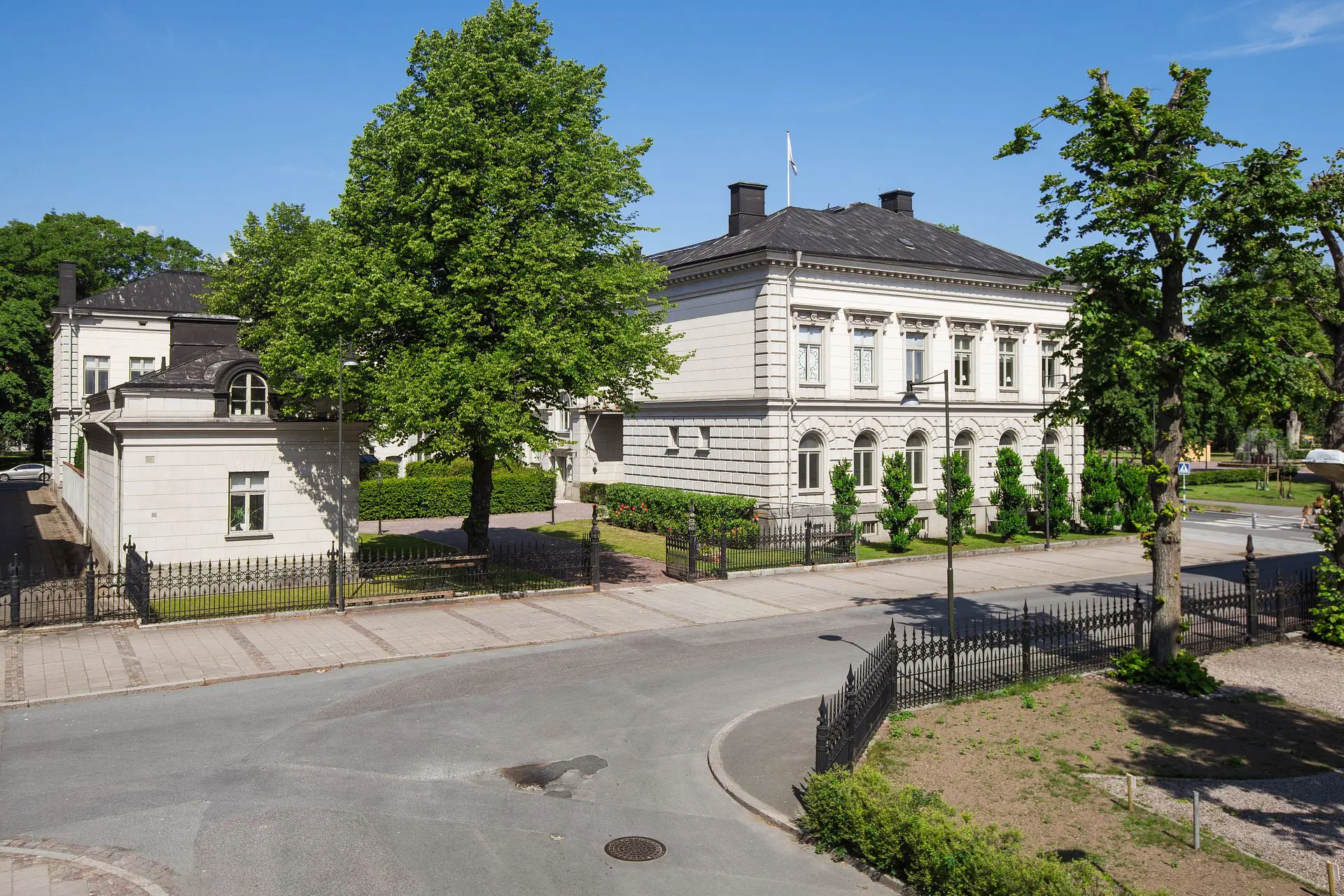 Residensets huvudbyggnad och sidobyggnad som vetter ut mot huvudgatan en solig sommardag.