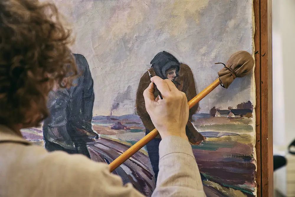 Målerikonservator Karin Hermerén i färd med att konservera en målning.