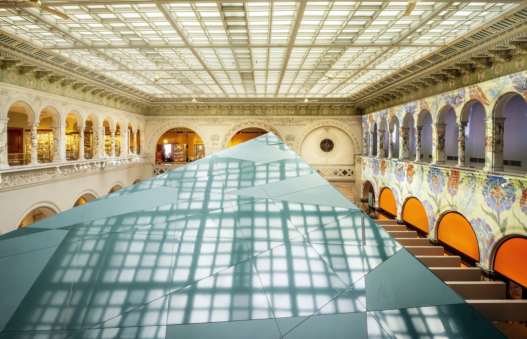 Översiktsbild av Medelhavsmuseets interiör, med rader av pelare och till höger väggmålningar.