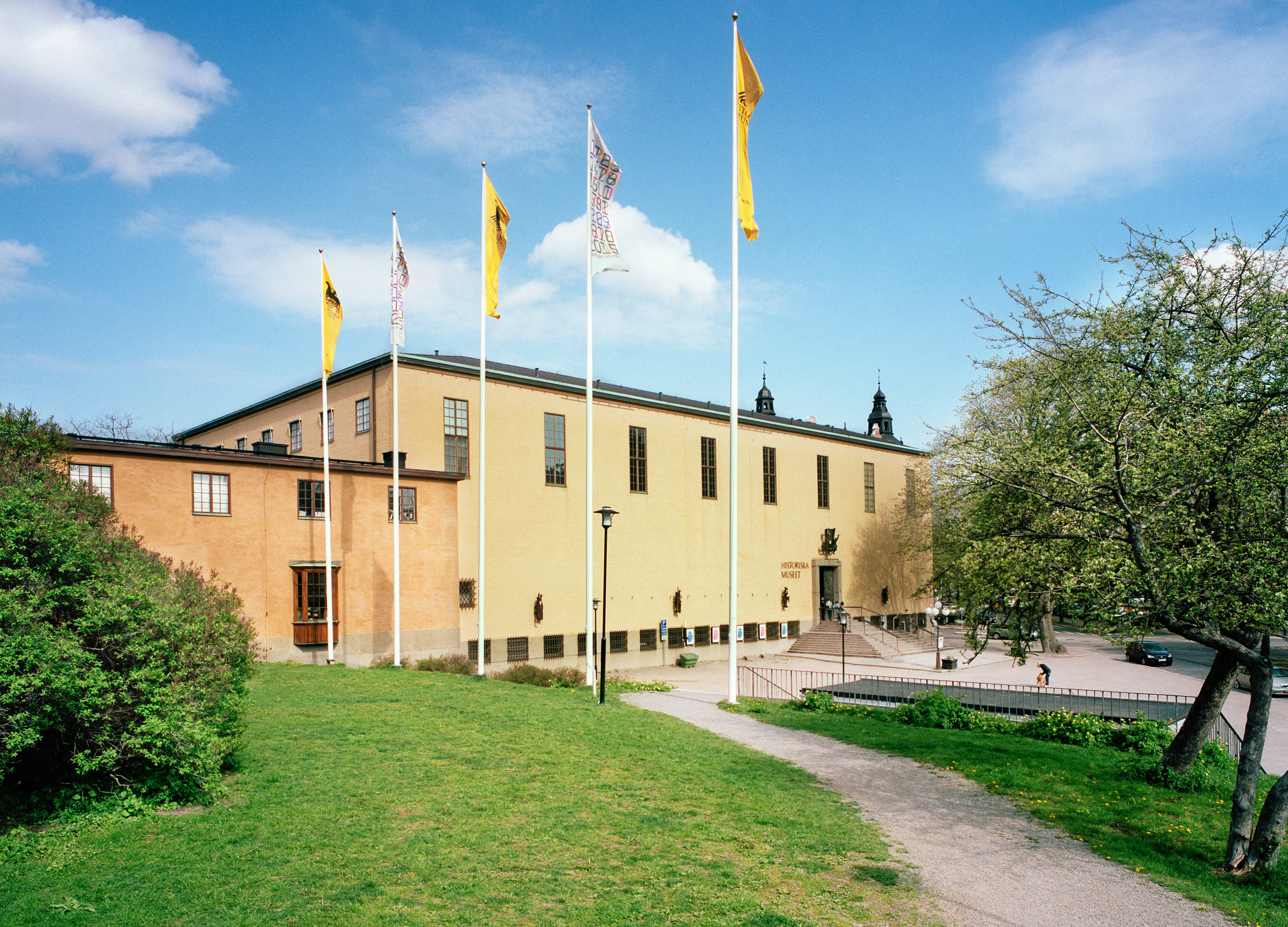 Historiska museet i Stockholm. Entré-fasaden är slät och gulputsad. Längs övre våningen sitter en rad höga fönster.