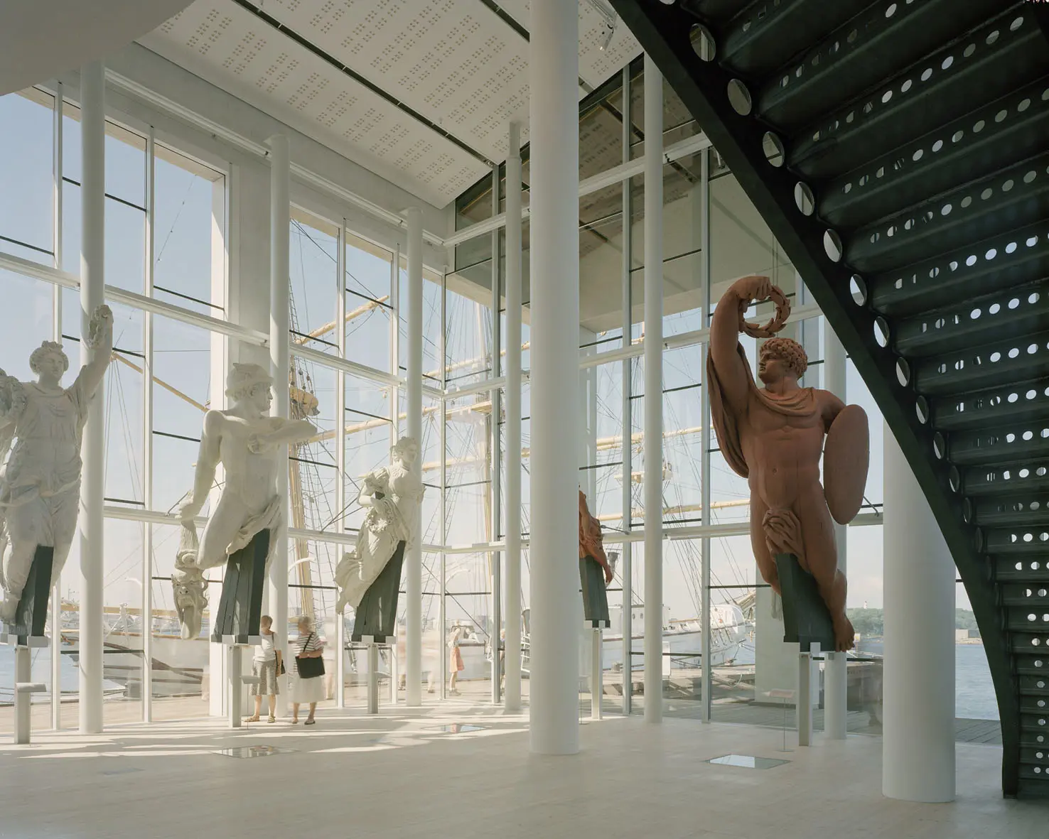 Galjonshallen i Marinmuseum. Två besökare ser väldigt små ut bland de stora galjonsfigurerna och hallens höga pelare.