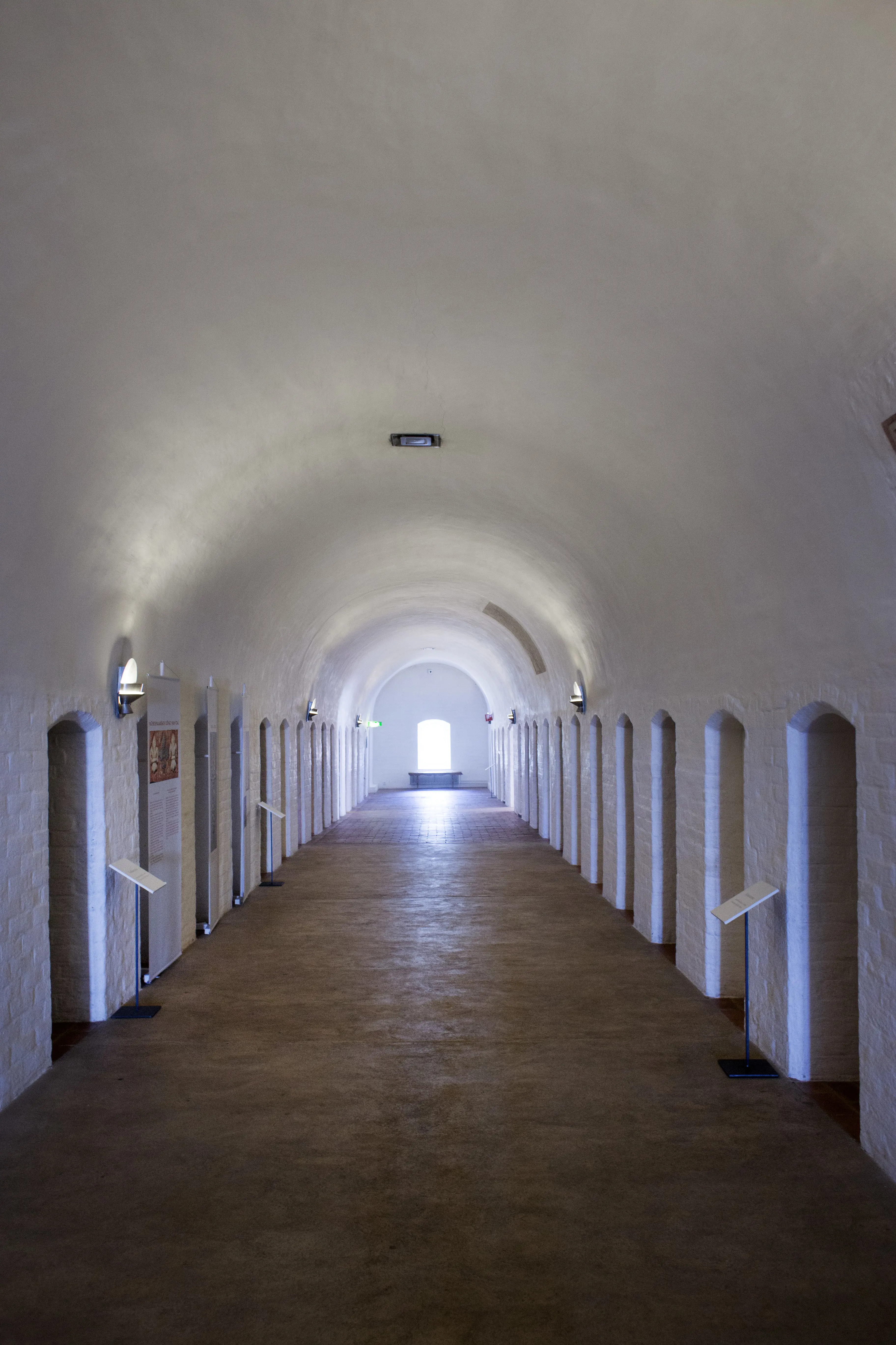 Interiör, nunneklostret i Vadstena. Dormitorium. En korridor med välvt tak. Längs väggarna leder dörrar in till sov-cellerna.